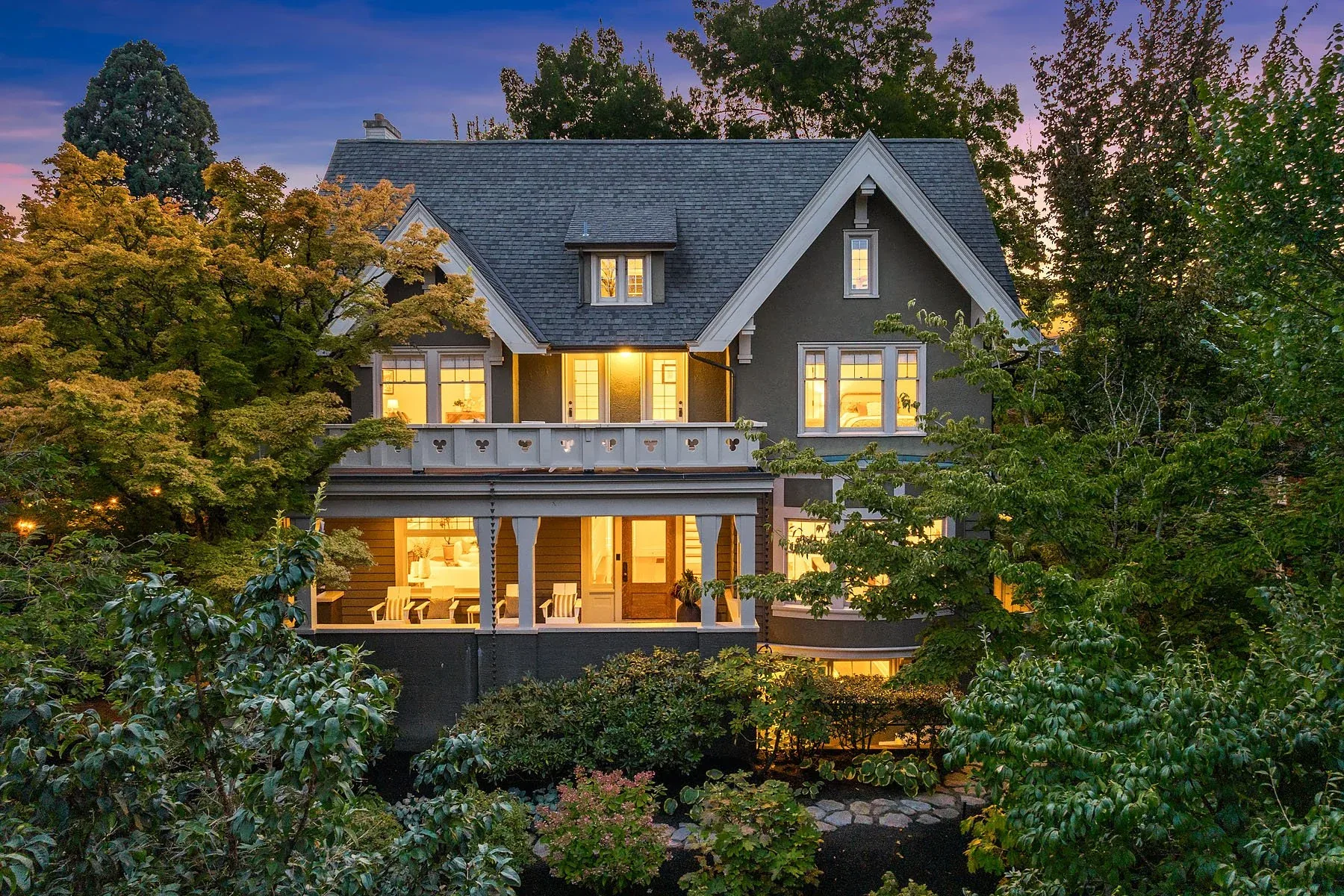 Capitol Hill classic home at dusk, a grand gray craftsman residence with glowing windows framed by mature trees