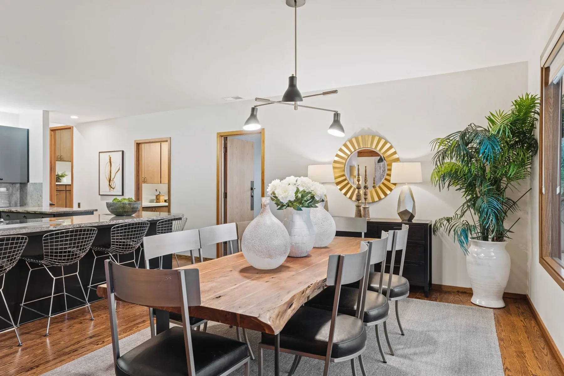 Seattle luxury home staging featuring a live-edge dining table beside a kitchen bar with wire stools and styled greenery