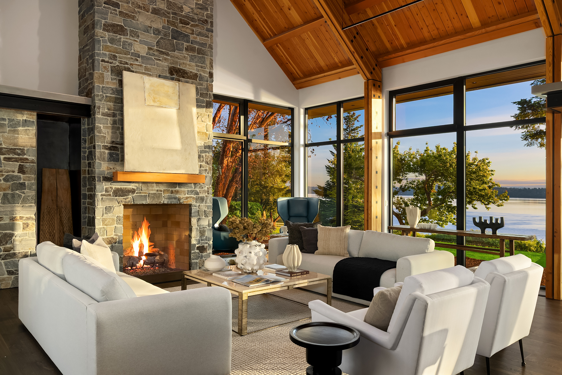 Fireside living room staged with crisp white sofas, a stone chimney, and framed views across the Bainbridge waterfront