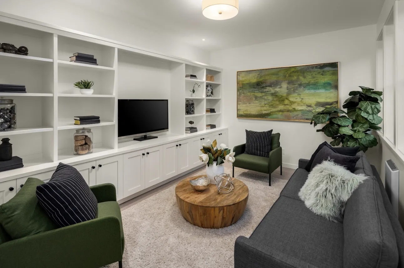 Family room staged by RD Interiors with built-in shelving, a round wood coffee table, and green-accented seating