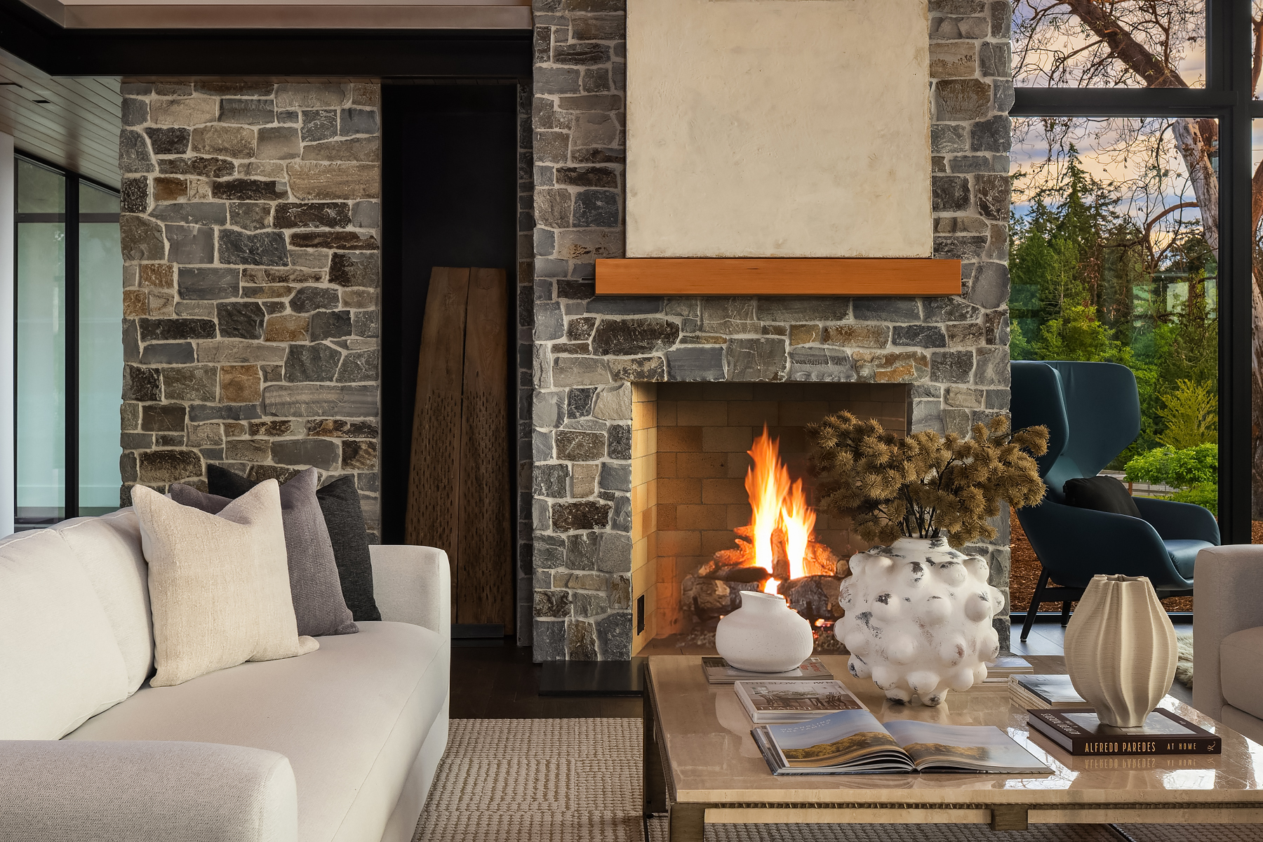 Modern fireplace vignette with stone surround, layered neutral furnishings, and styled coffee table details in a staged Bainbridge home