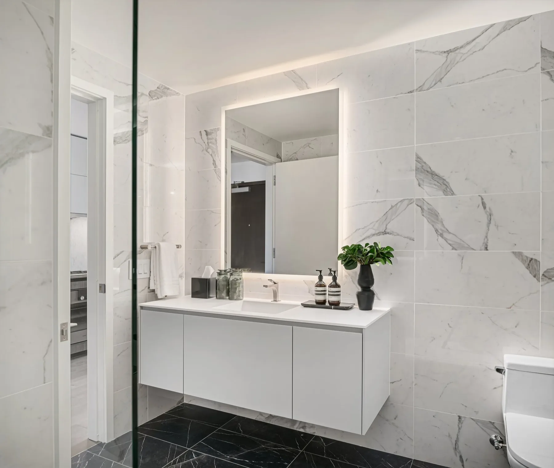 Contemporary bathroom in a Seattle high-rise residence with marble walls, a floating vanity, and a glass walk-in shower