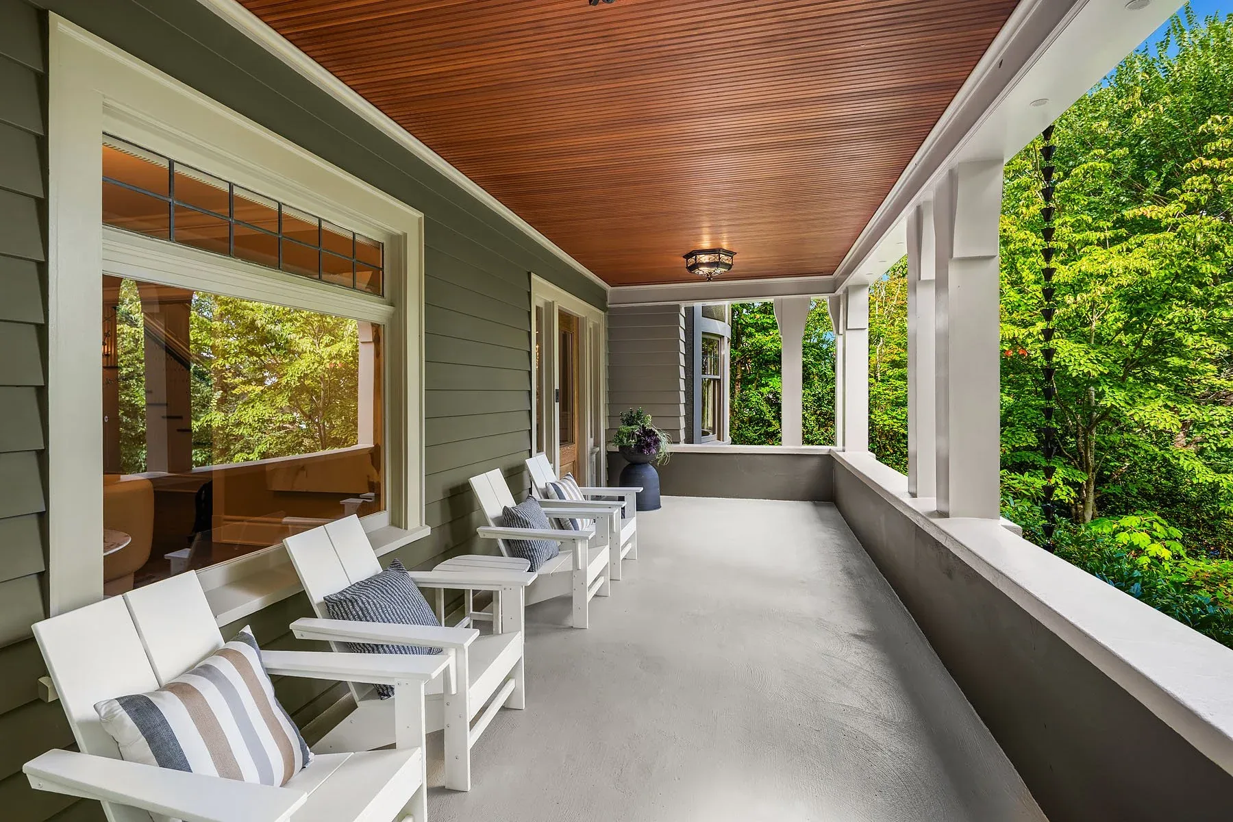 Capitol Hill home staging featuring a covered side porch with a wood ceiling and white seating overlooking the trees