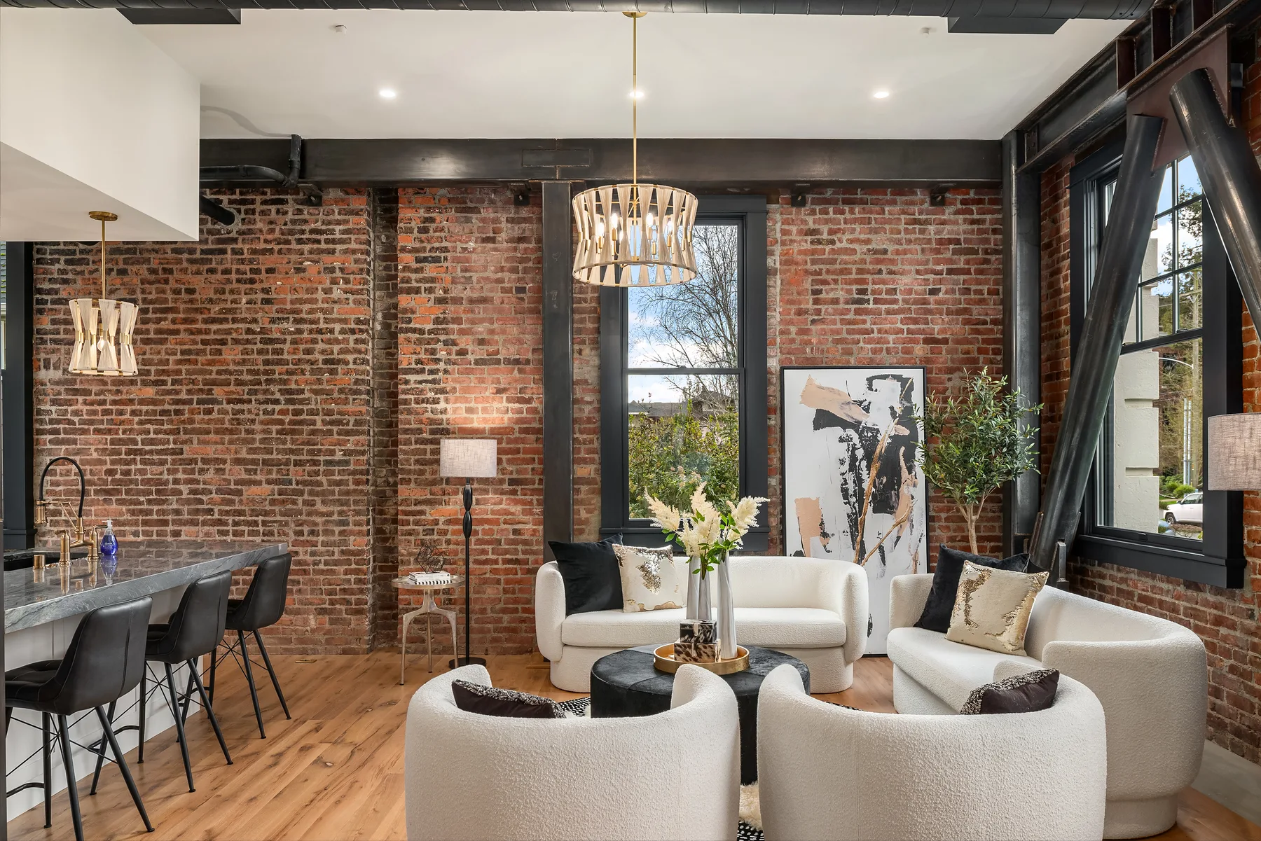 Living room with exposed brick walls, blackened steel beams, and a woven drum chandelier
