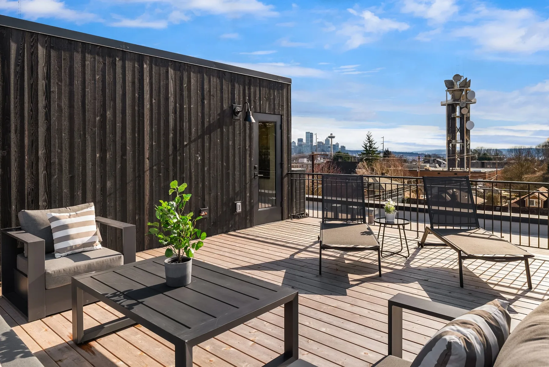 Rooftop deck staged with outdoor lounge seating and sweeping views of the Seattle skyline