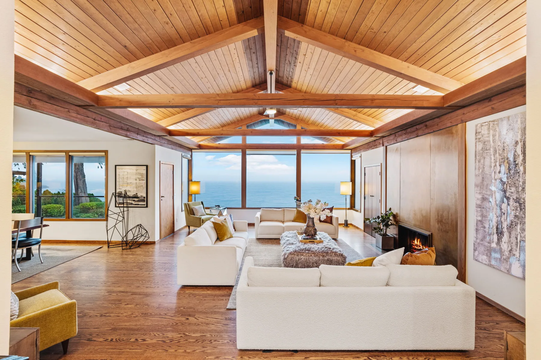 Great room with a beamed cedar ceiling and floor-to-ceiling windows framing a water view