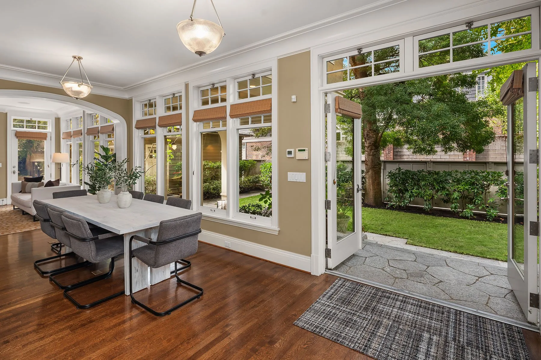 Seattle home staging featuring a bright breakfast area with a white table, sling chairs, and French doors opening to the garden