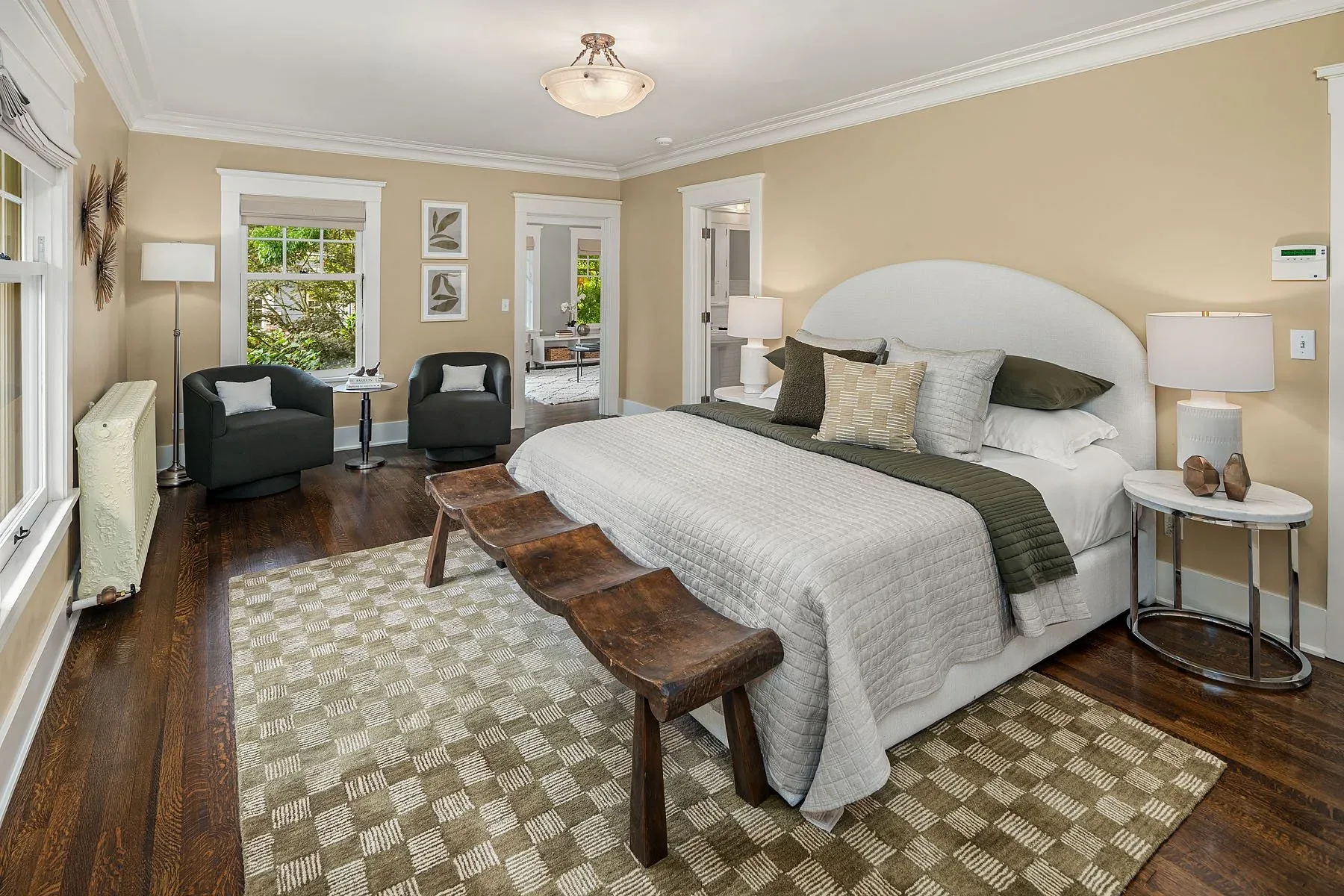 Seattle luxury listing staging with a serene primary bedroom, upholstered bed, wood bench, and a pair of reading chairs