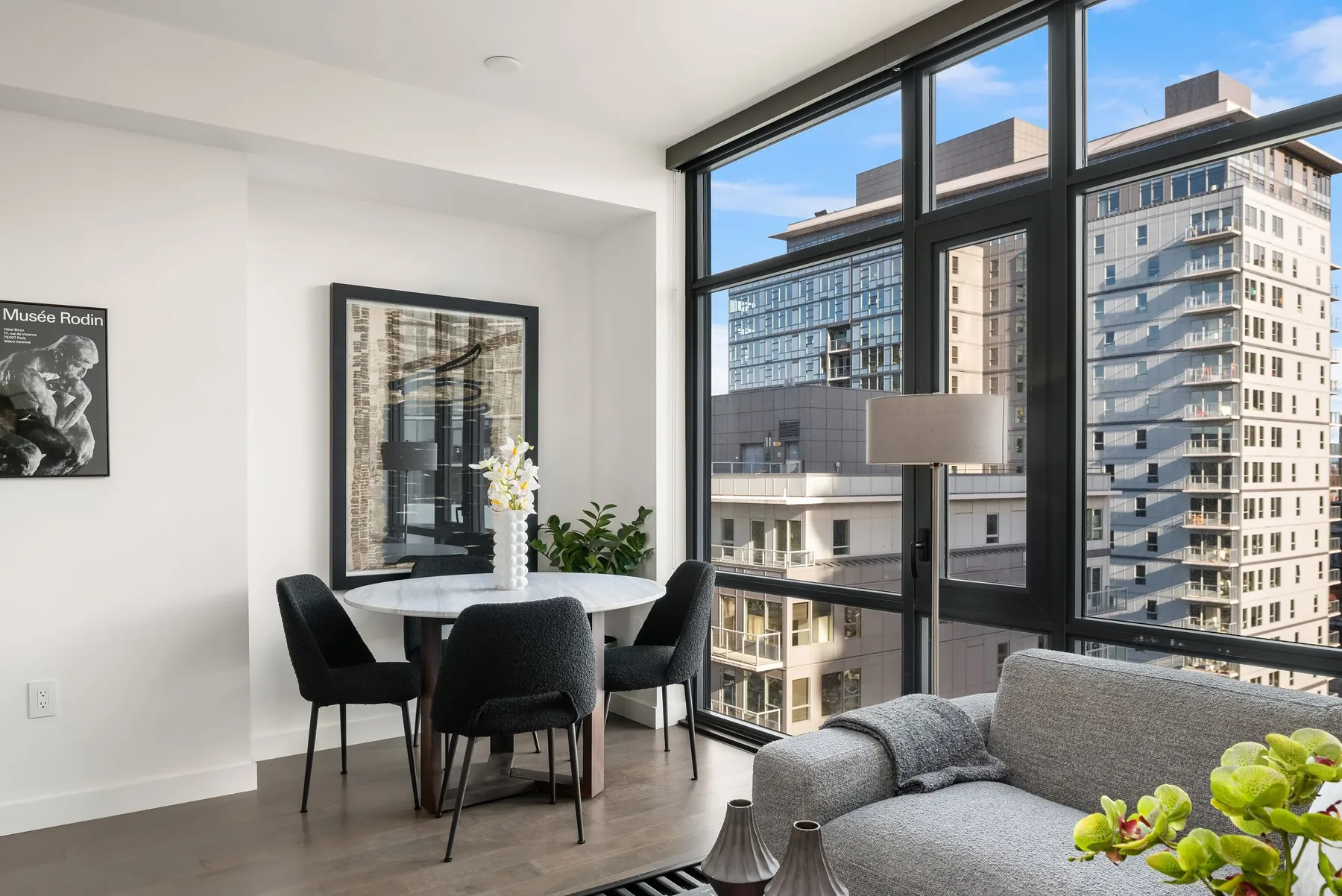 Downtown Seattle home staging with a dining nook and lounge set against floor-to-ceiling windows overlooking the city towers