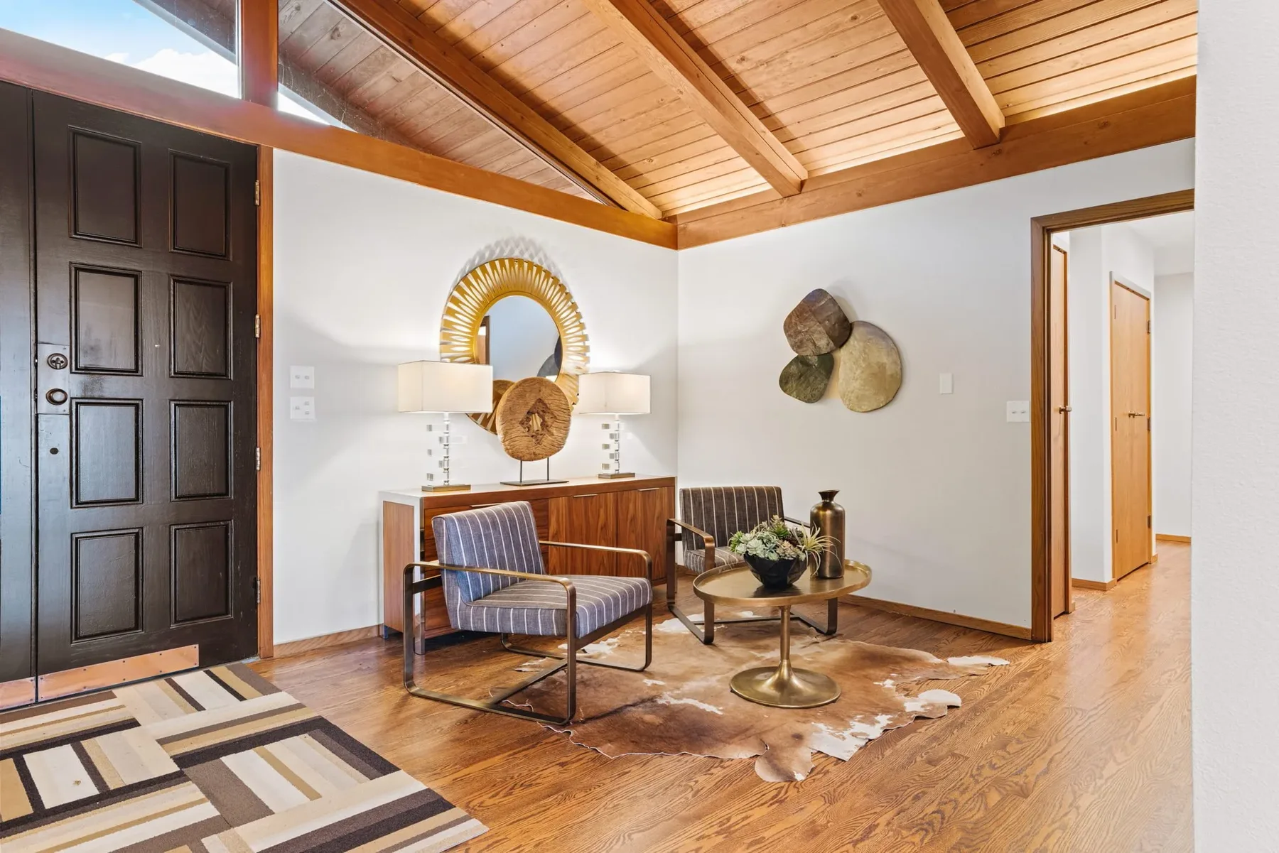 Entry sitting area staged by RD Interiors with patterned armchairs, a sunburst mirror, and a curated console