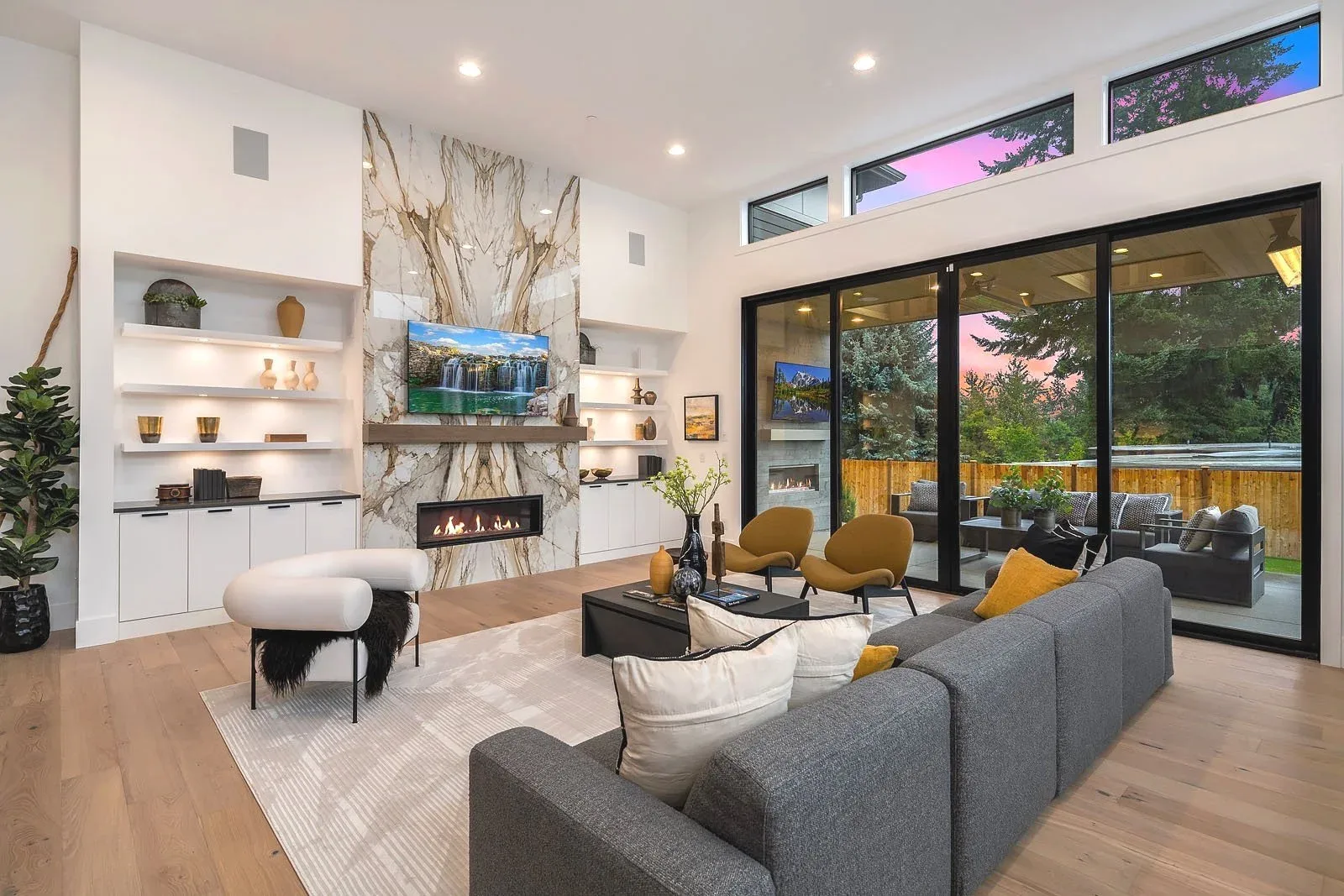 Modern living room staged by RD Interiors with a floor-to-ceiling marble fireplace feature wall and sliding glass doors to the patio
