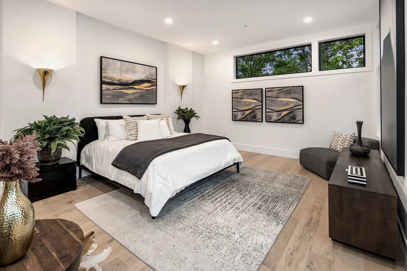 Seattle luxury home staging featuring a serene primary bedroom with neutral bedding, framed art, and a wood accent wall