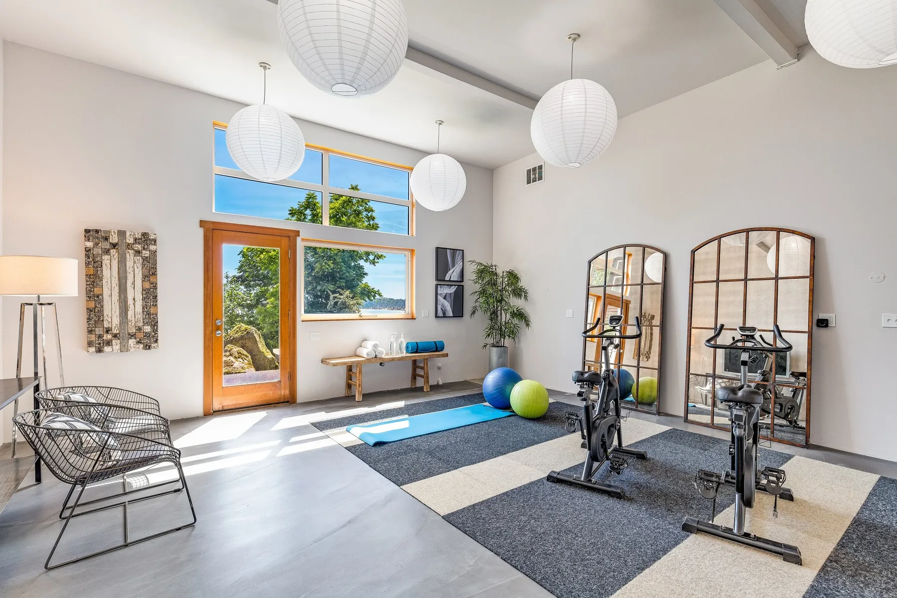 Home gym staged with exercise equipment, arched mirrors, and natural light from oversized windows