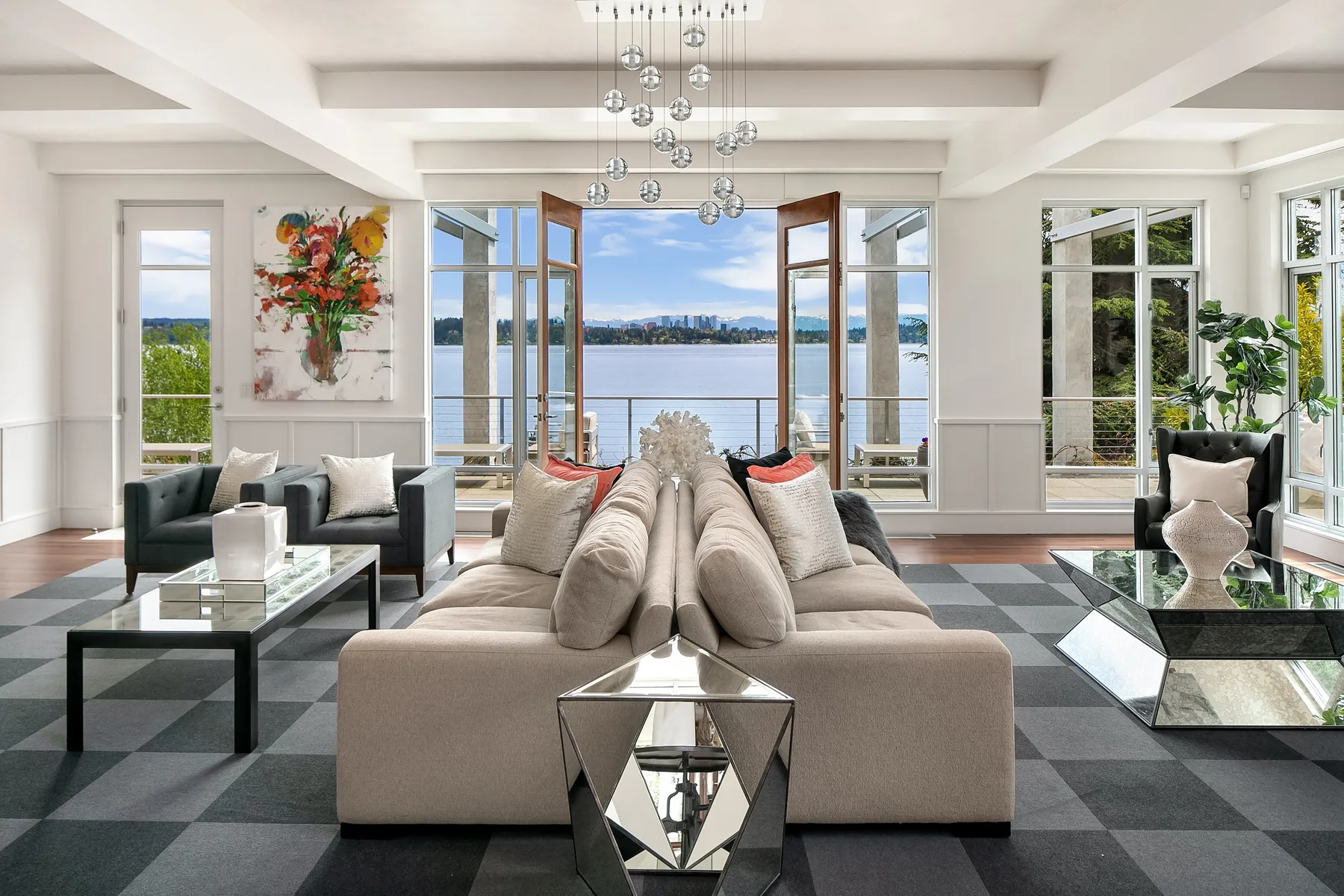 Seattle luxury home staging featuring a living room with French doors open to the lake, a neutral sofa, and faceted mirror tables