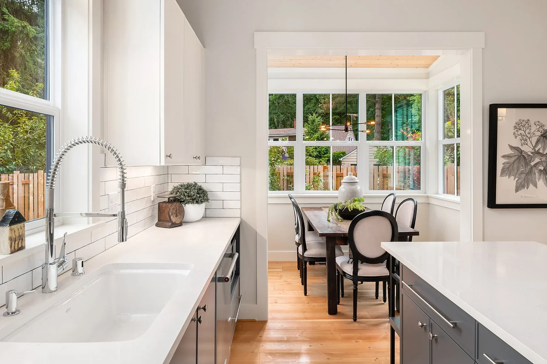 Seattle luxury home staging featuring a bright kitchen with a farmhouse sink, subway tile, and a wood dining table in a window-lined nook