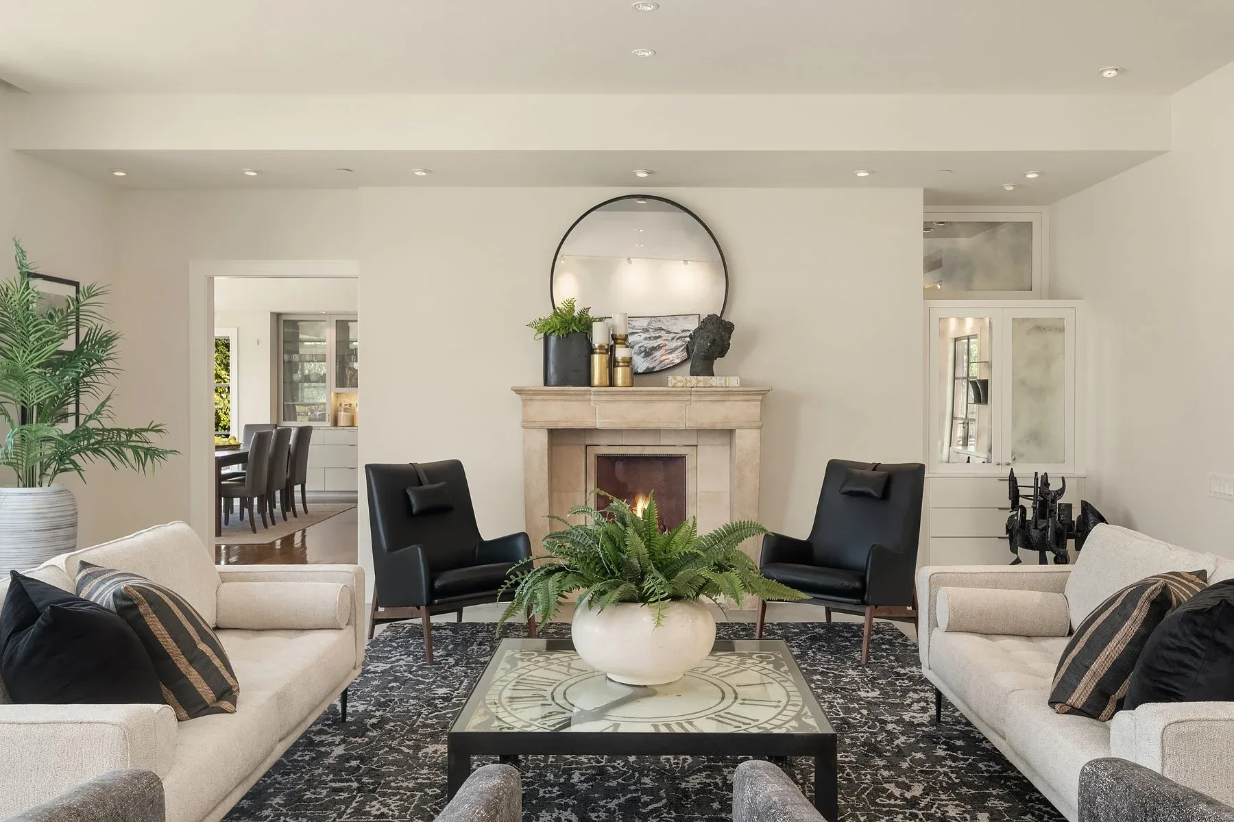 Seattle luxury home staging featuring a living room with a stone fireplace, twin black leather chairs, and a view through to the dining room