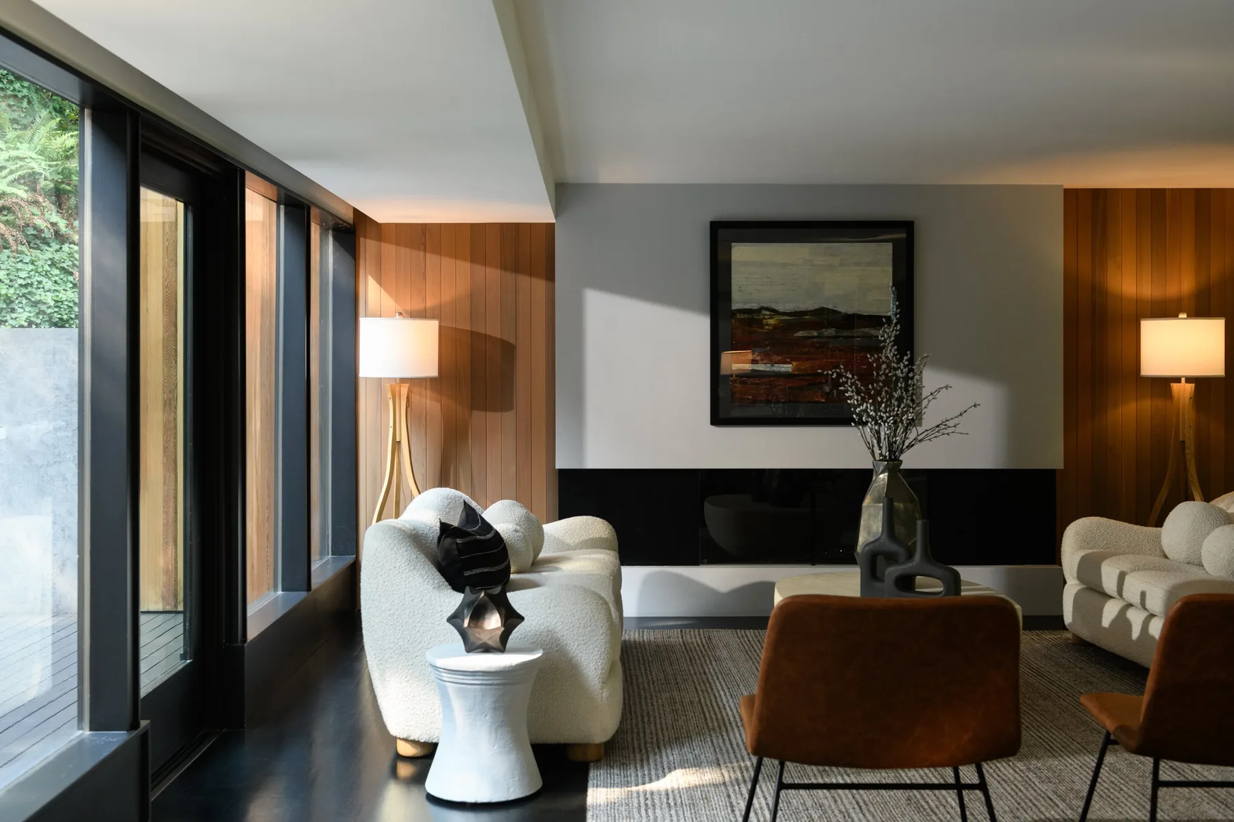 Modern living room staged by RD Interiors with warm wood paneling, a floor lamp, and views to the patio