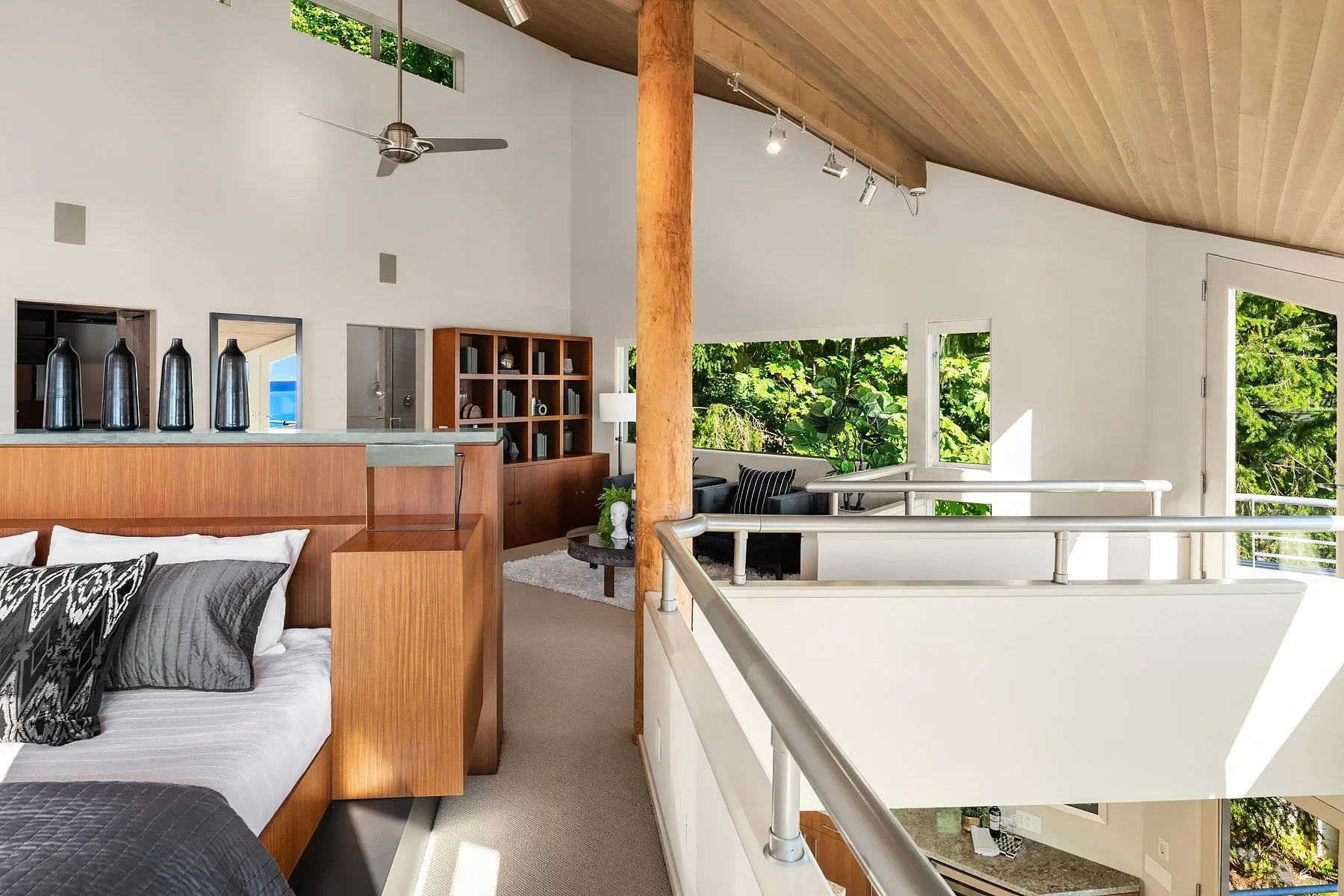 Primary bedroom loft staged with a wood-paneled headboard, cedar ceiling, and an open railing overlooking the living space below