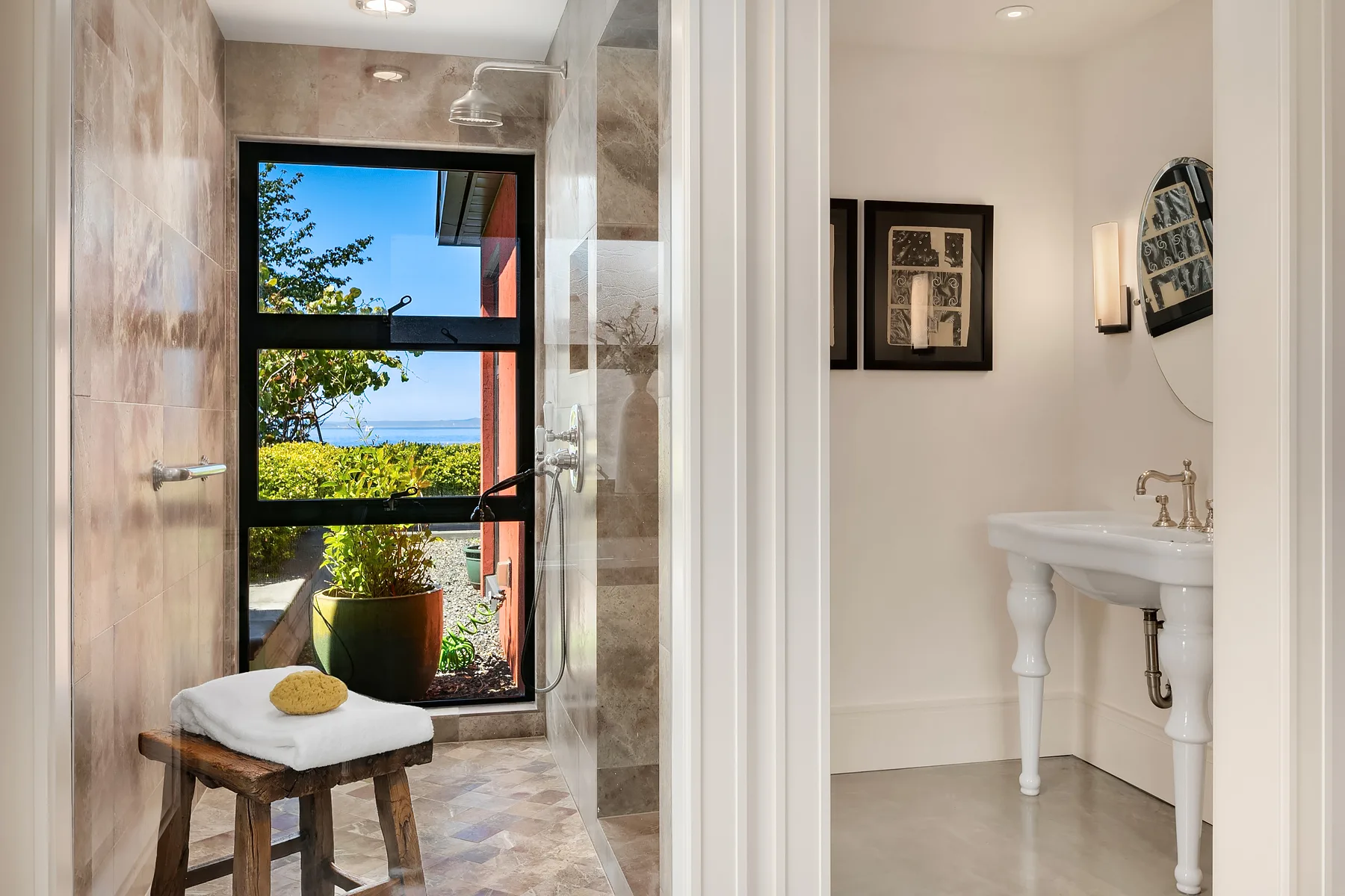 Spa-like bathroom with a stone walk-in shower, water-view window, and a classic pedestal sink
