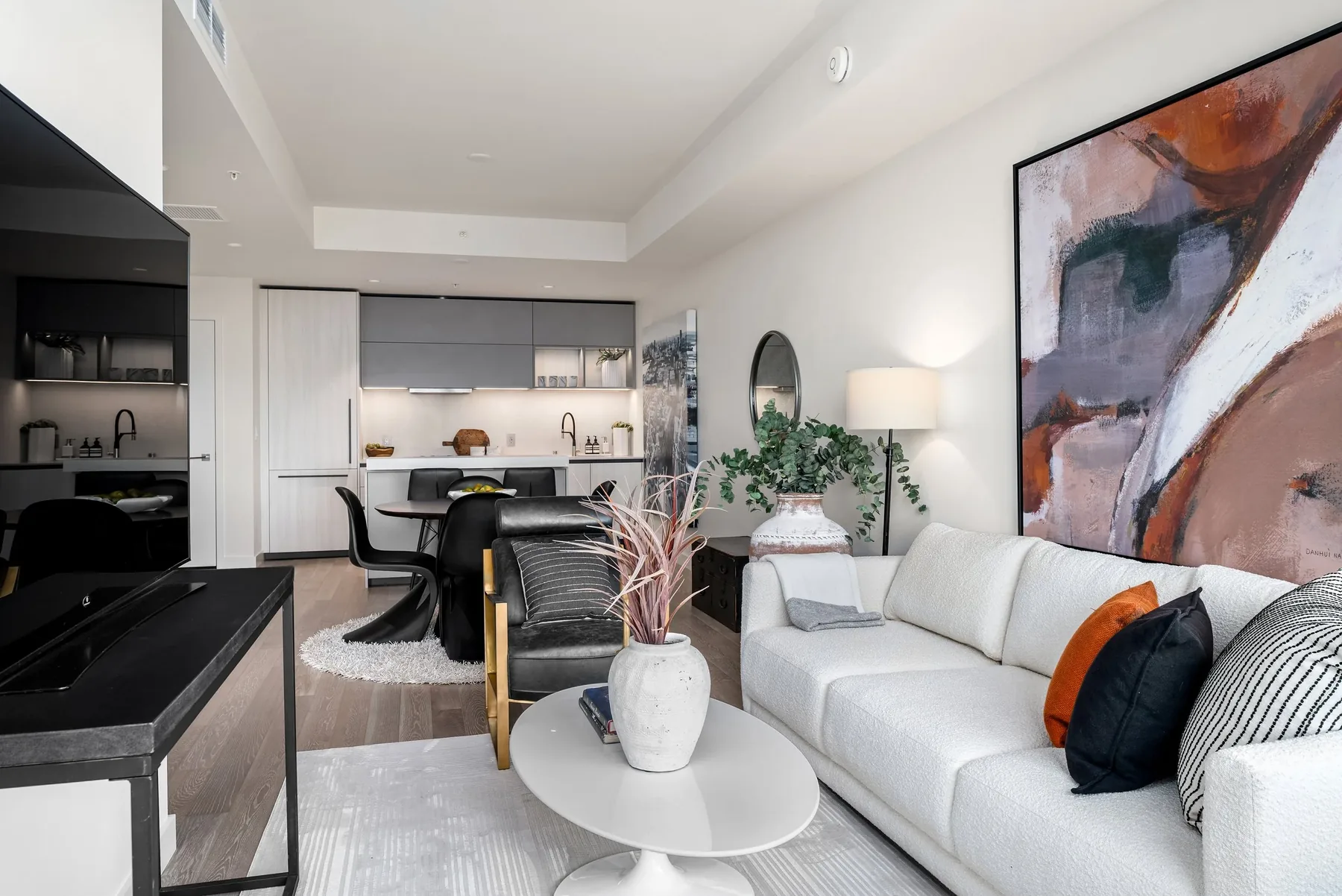 Downtown Seattle home staging featuring an open living and kitchen space with a white sofa, sculptural pedestal table, and large abstract artwork