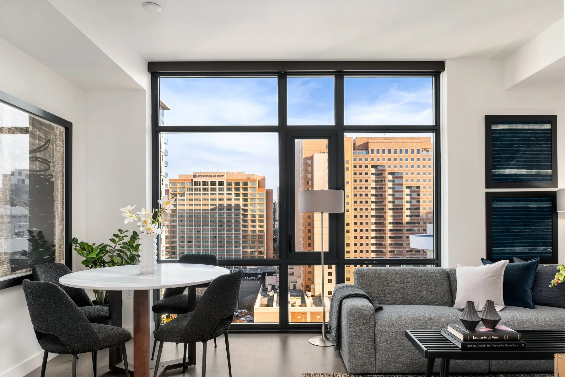 Seattle luxury listing staging featuring a combined dining and living area with a round marble table and sweeping skyline views