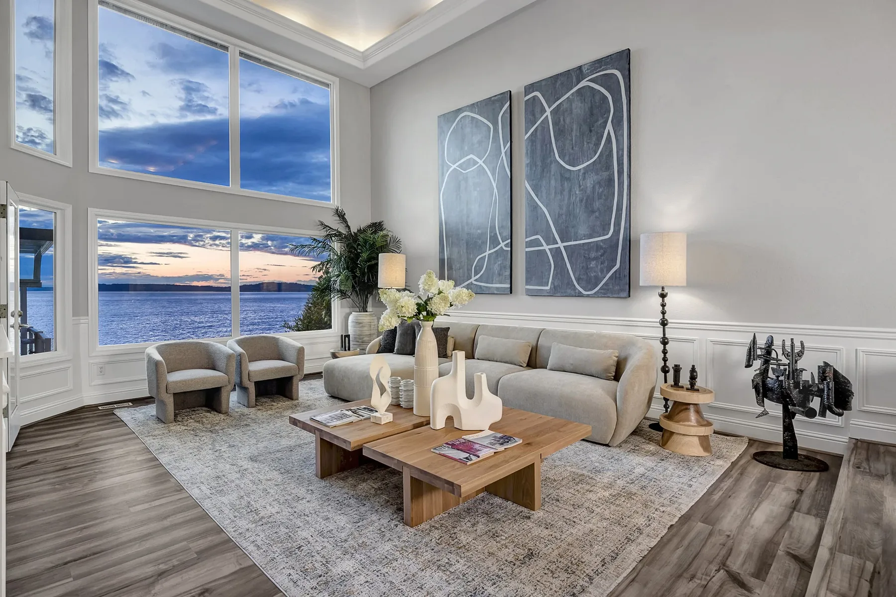 Luxury listing staging with a serene living room at dusk, neutral sofa, and tall windows framing the water