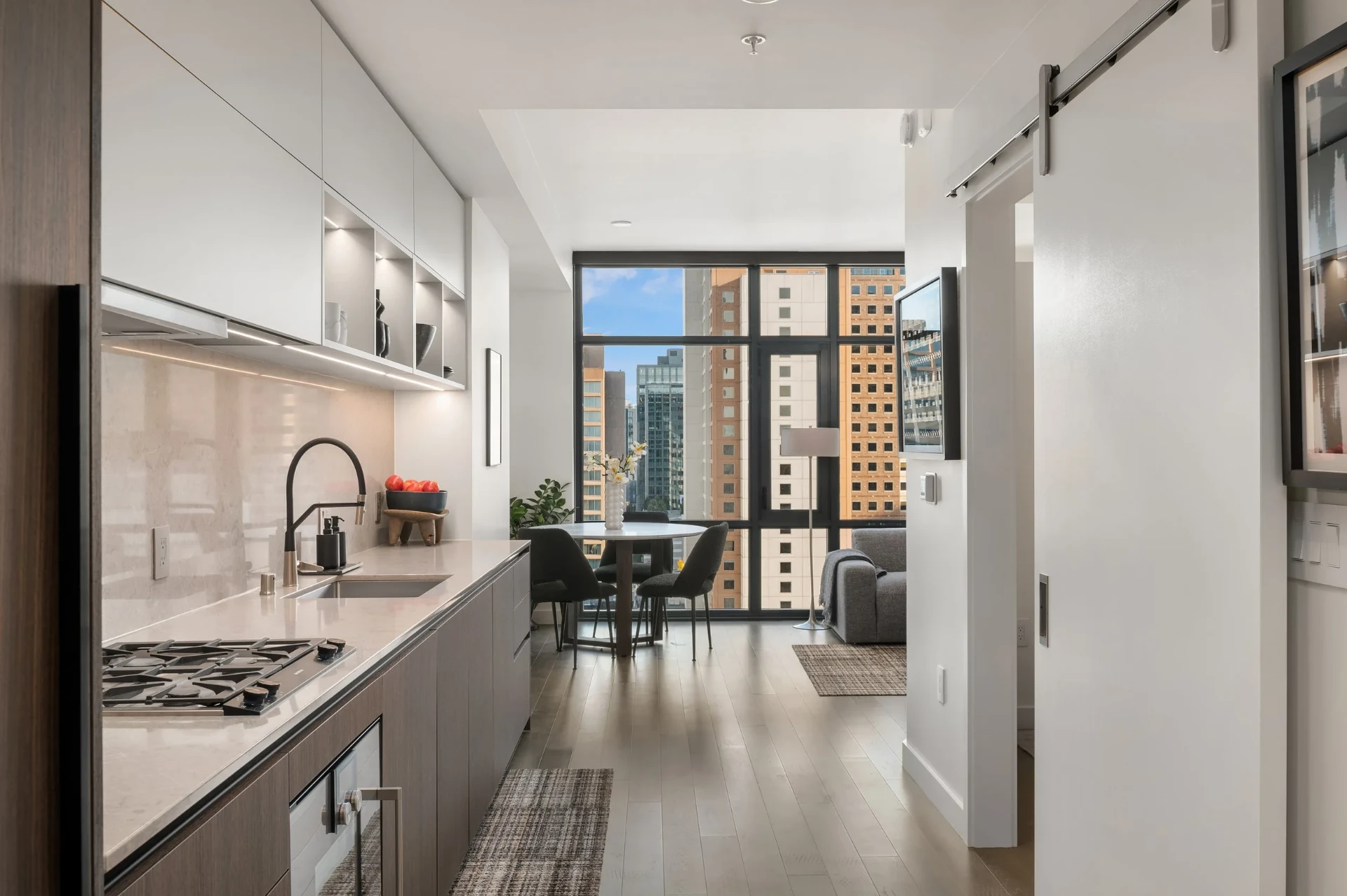 A bright modern downtown condo kitchen and dining area with skyline views, staged by RD Interiors
