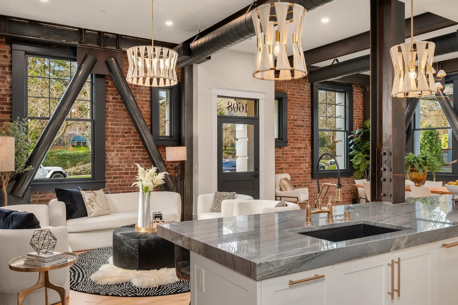 Seattle luxury home staging featuring an open great room with exposed brick walls, blackened steel beams, and layered living and dining furnishings