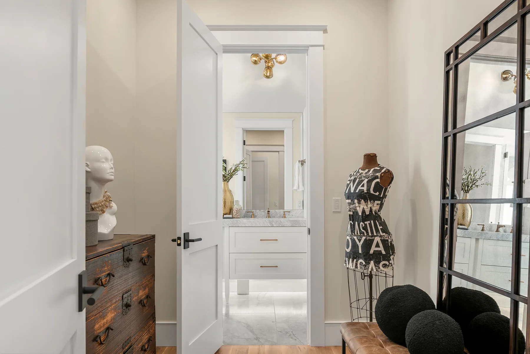 Dressing area and ensuite bath with a custom vanity, large mirror, and styled decor