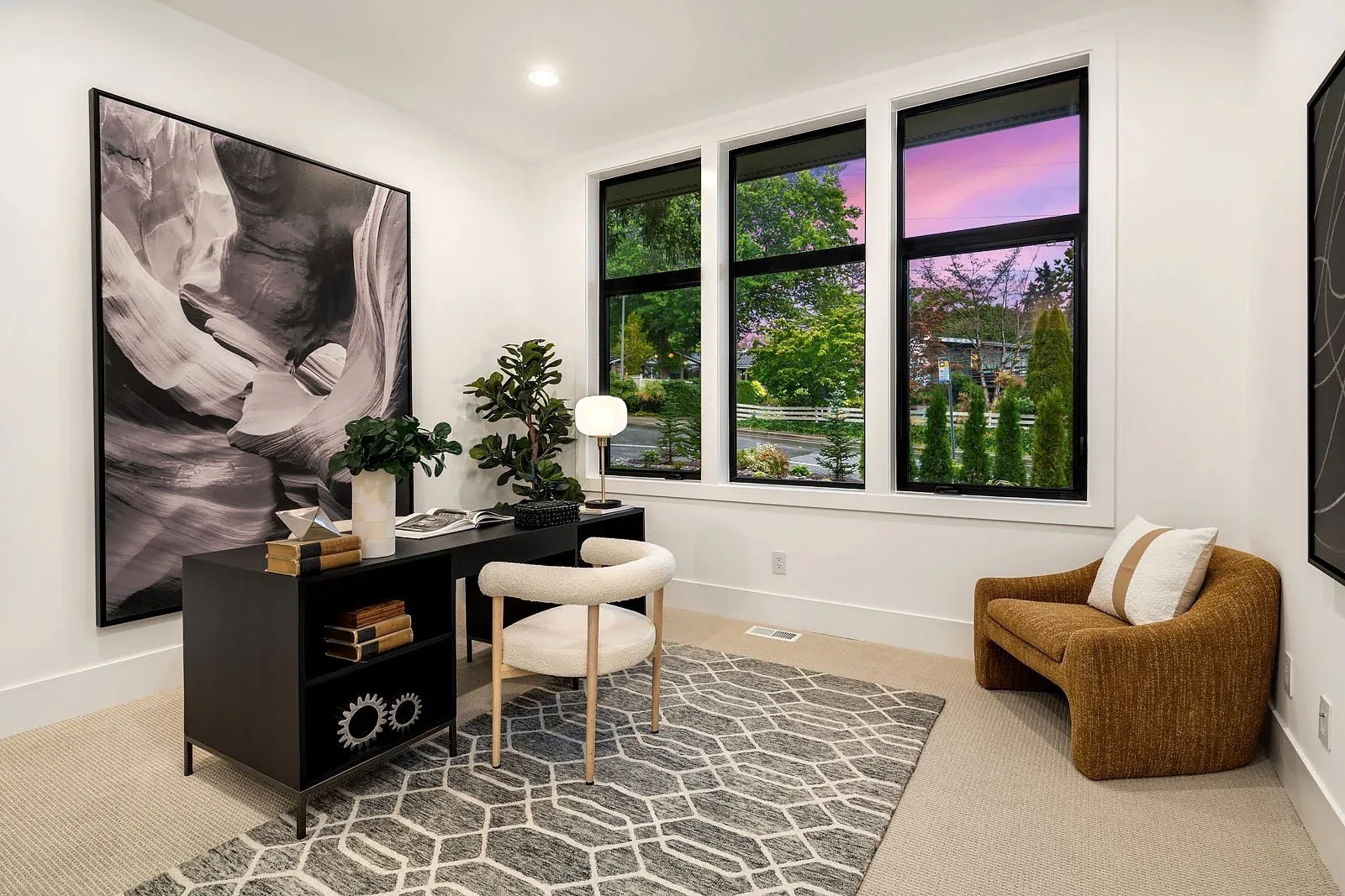 Flexible bonus room staged as a home office with a writing desk, accent chair, and large-scale photography