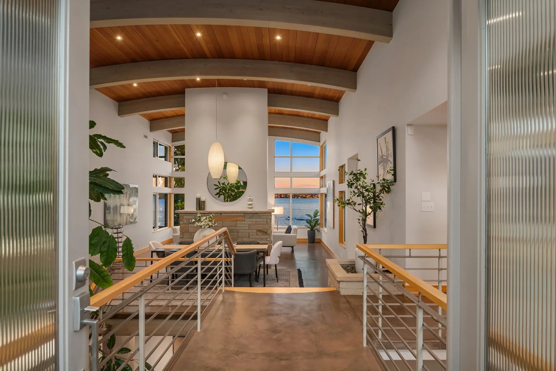 Seattle luxury home staging featuring a contemporary entry landing with a curved wood ceiling, glass railings, and lake views