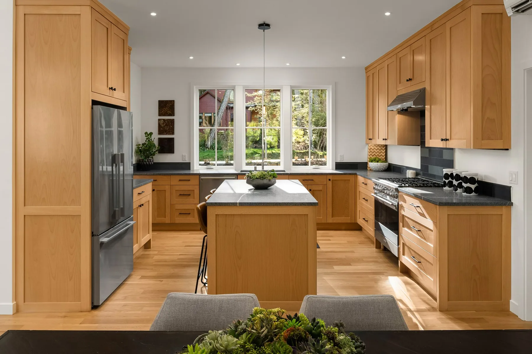 Seattle luxury home staging featuring a warm wood kitchen with a center island, stainless appliances, and a garden window