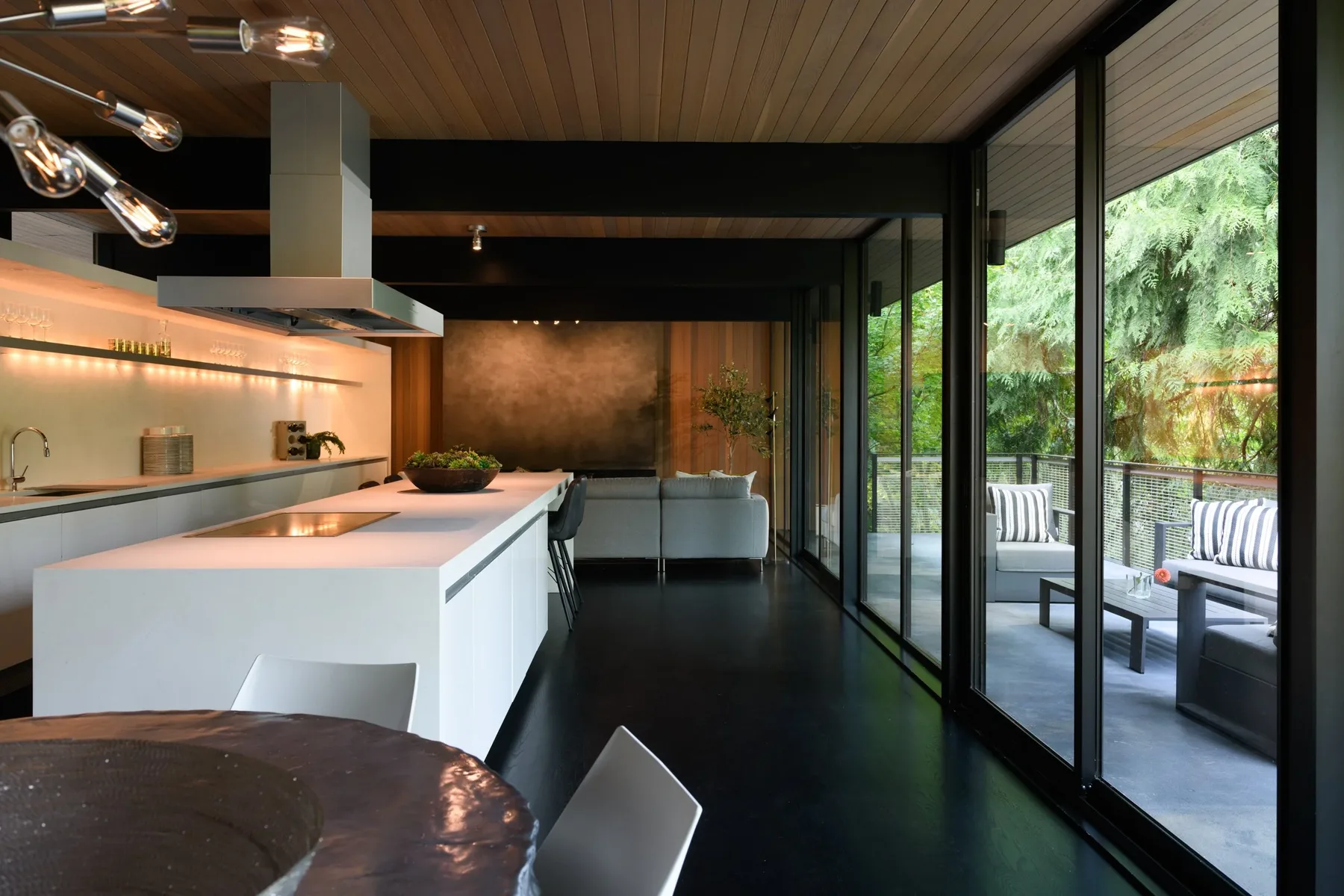 Modern Mercer Island kitchen staged with a white waterfall island, statement chandelier, and walls of glass