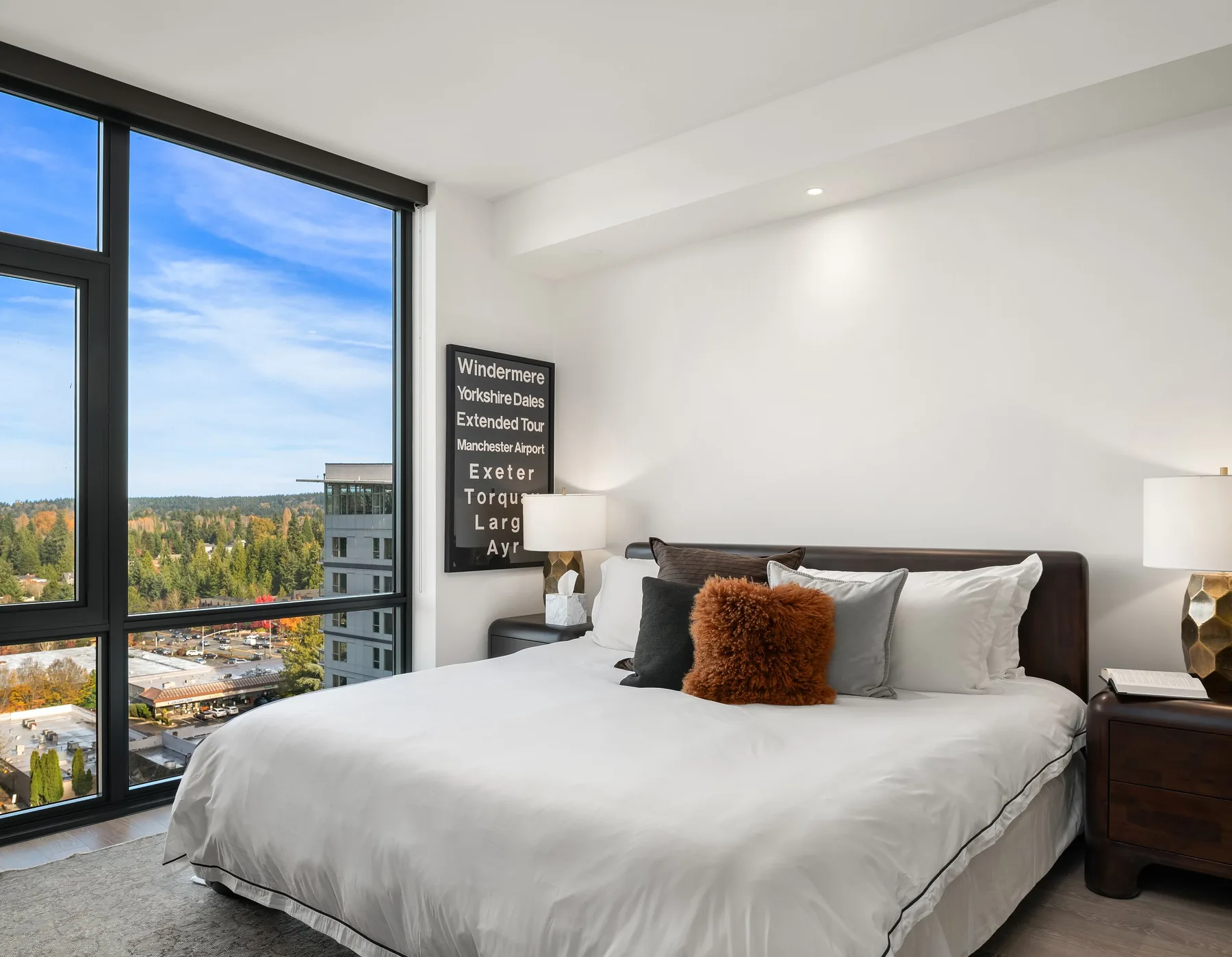 Seattle home staging with a serene high-rise bedroom, upholstered bed, and a corner window framing the downtown skyline
