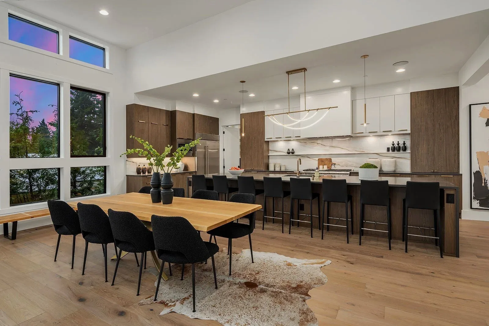 Modern new-construction kitchen and dining area staged by RD Interiors with a large island, bar seating, and walls of glass