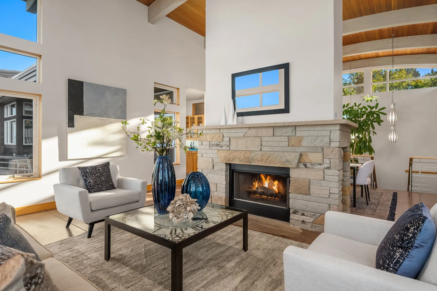 Fireside living room staged by RD Interiors with a stacked-stone fireplace, bouclé seating, and exposed wood beams