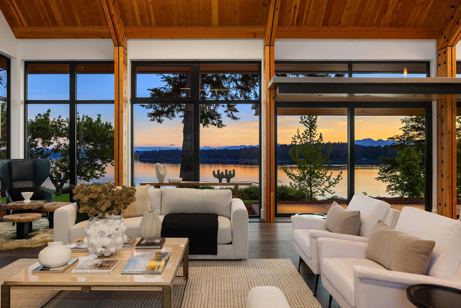 Evening waterfront sitting area staged with tailored white upholstery and glowing sunset views beyond the glass