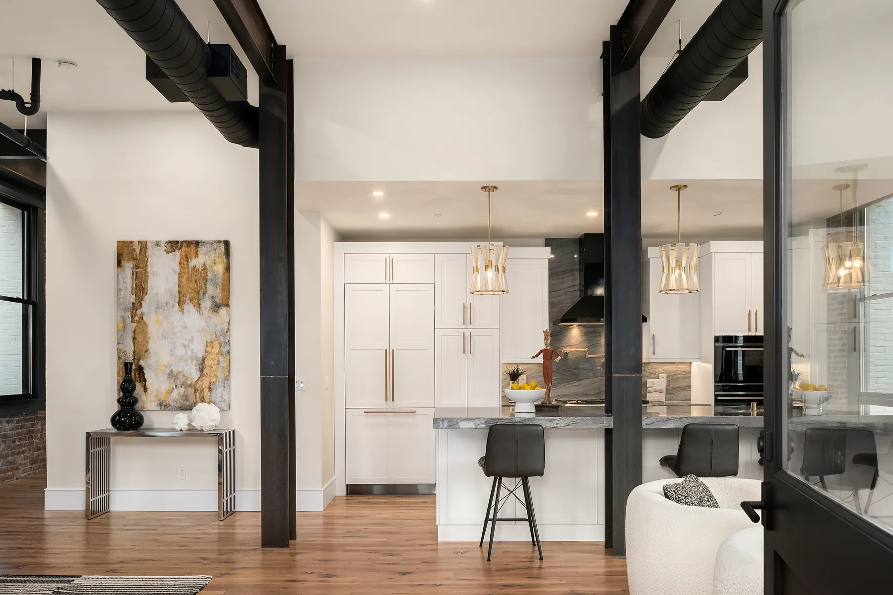 Modern kitchen with white cabinetry, a marble island, and woven pendant lighting