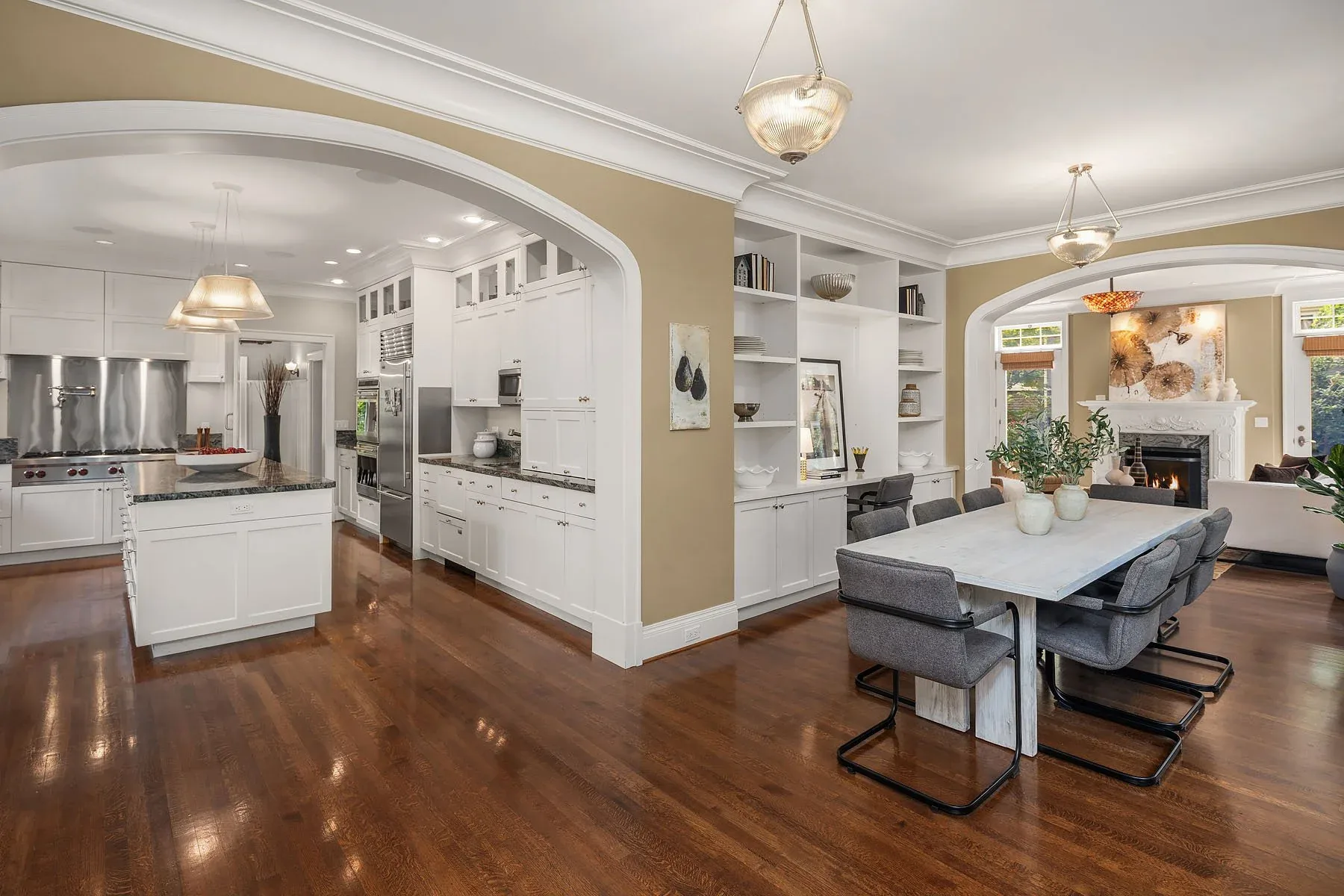 Luxury home staging in Seattle with a white chef's kitchen, marble island, and an arched opening to the dining room