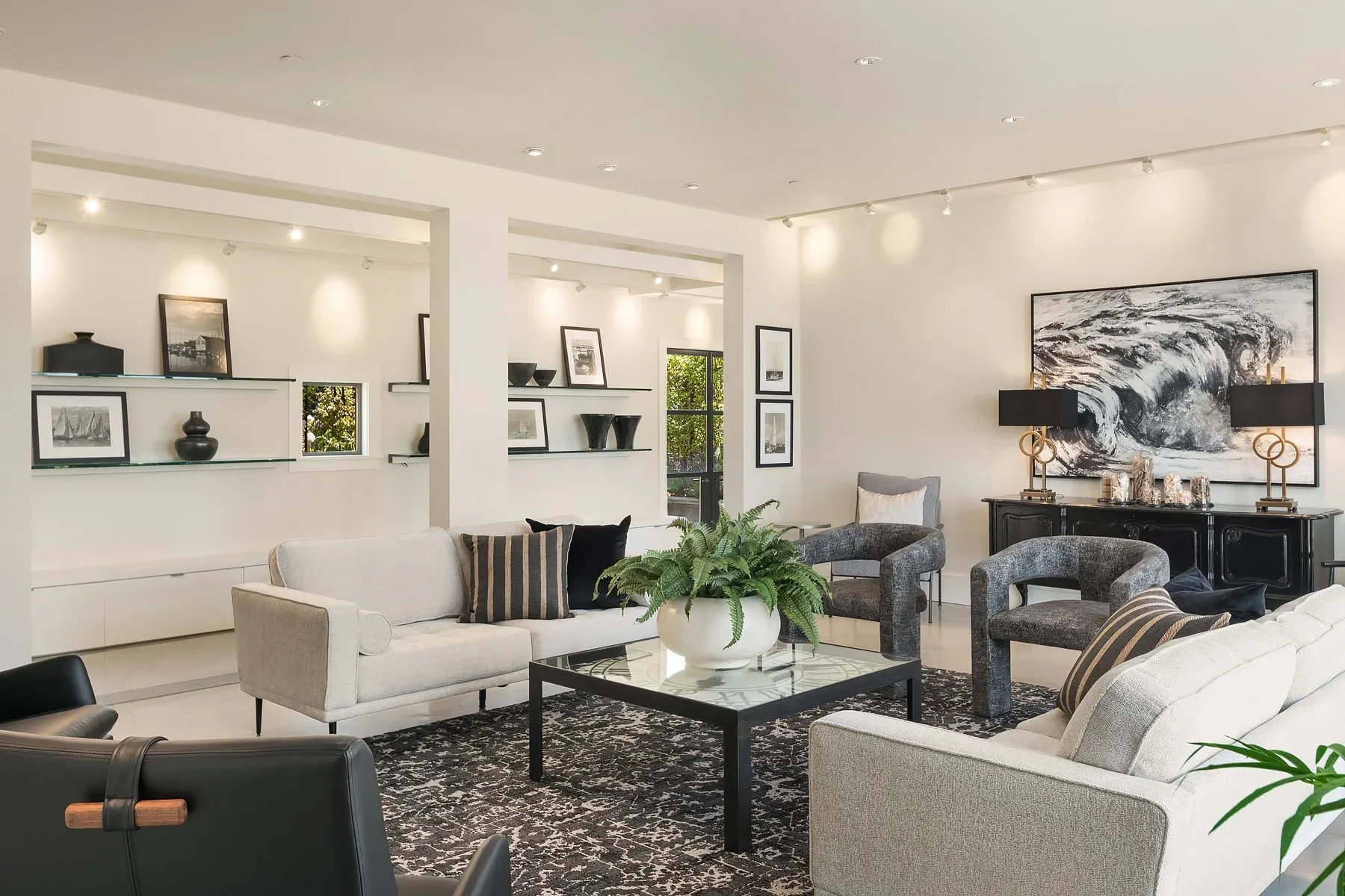 Gallery-style living room staged with floating shelves, a large black-and-white wave painting, and layered neutral seating