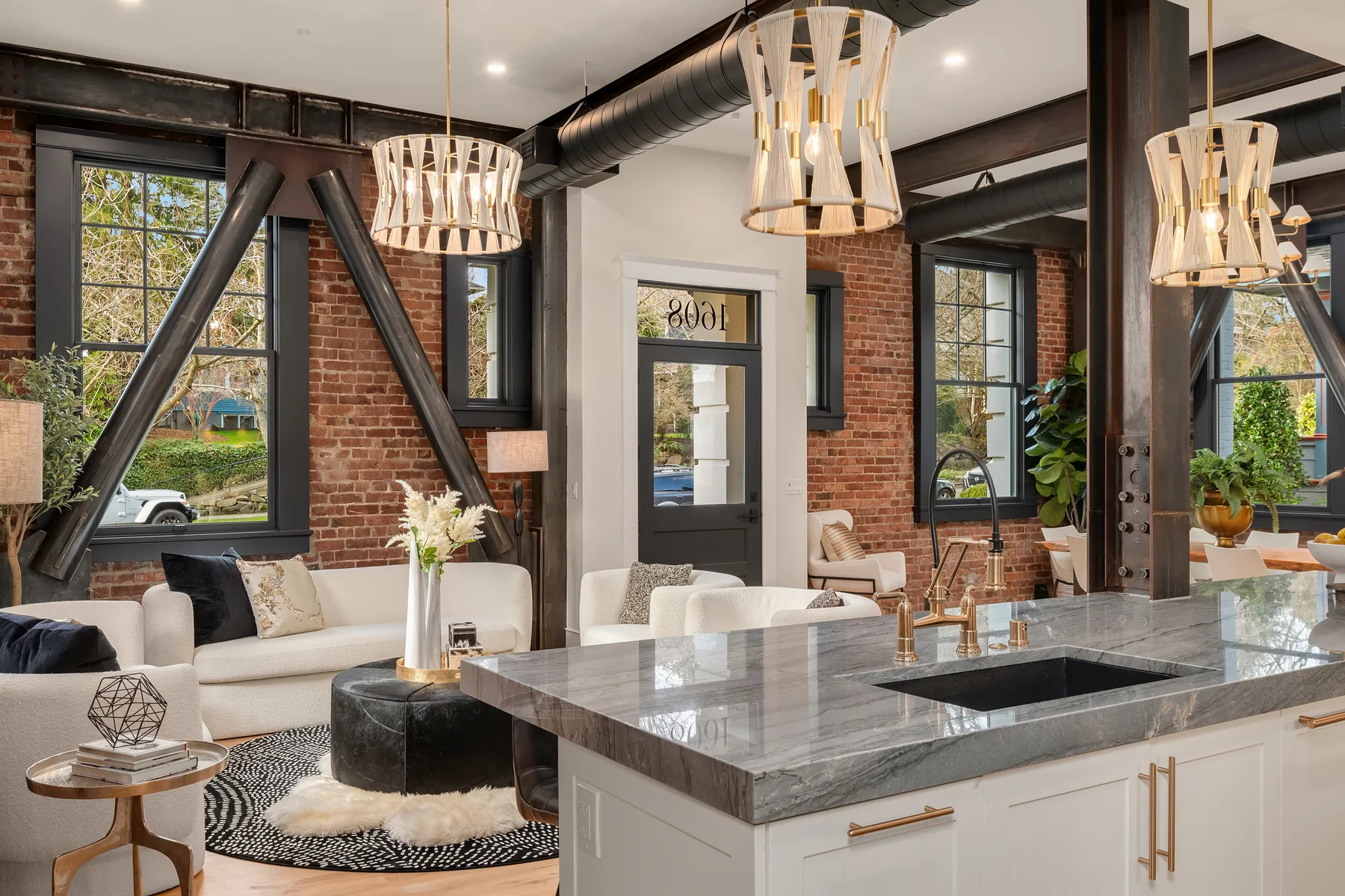 Chef's kitchen with a grey marble waterfall island, brass fixtures, and exposed timber trusses
