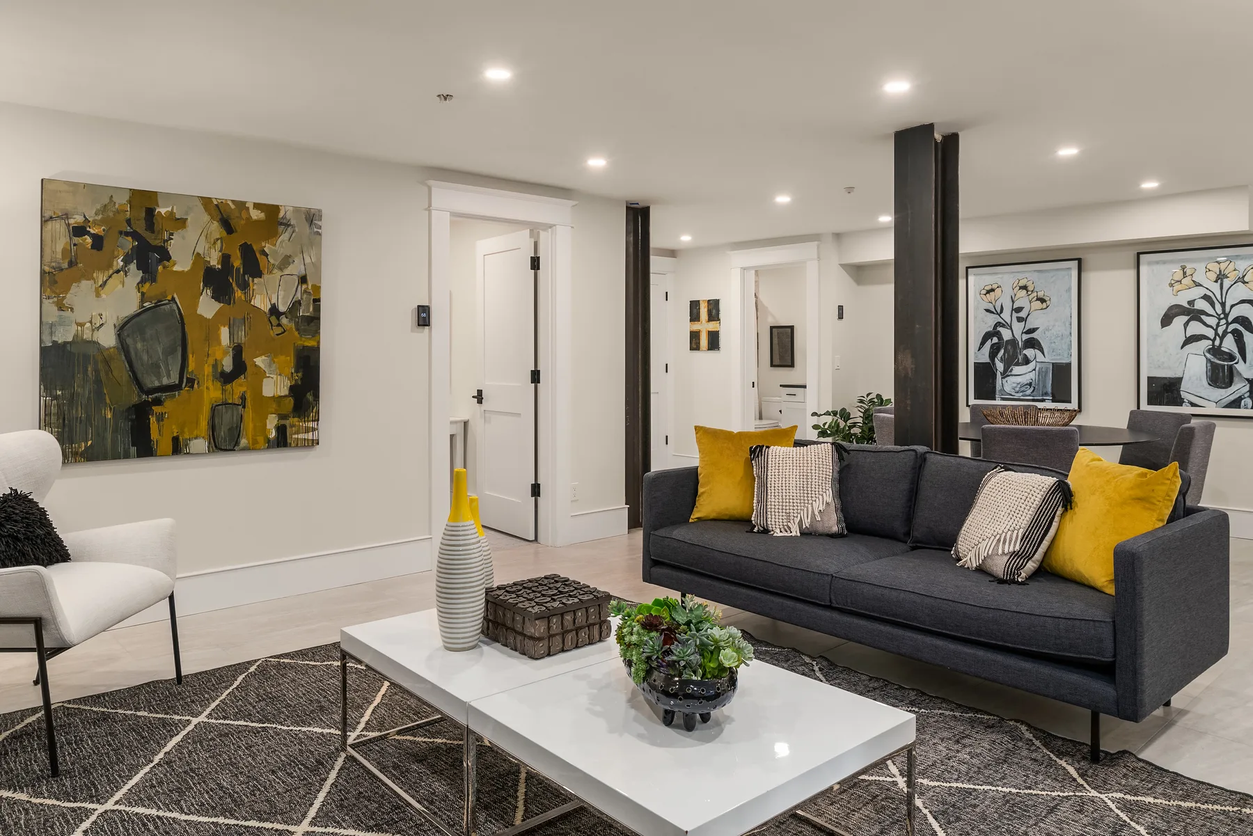 Family room staged with a charcoal sofa, layered rug, and abstract artwork