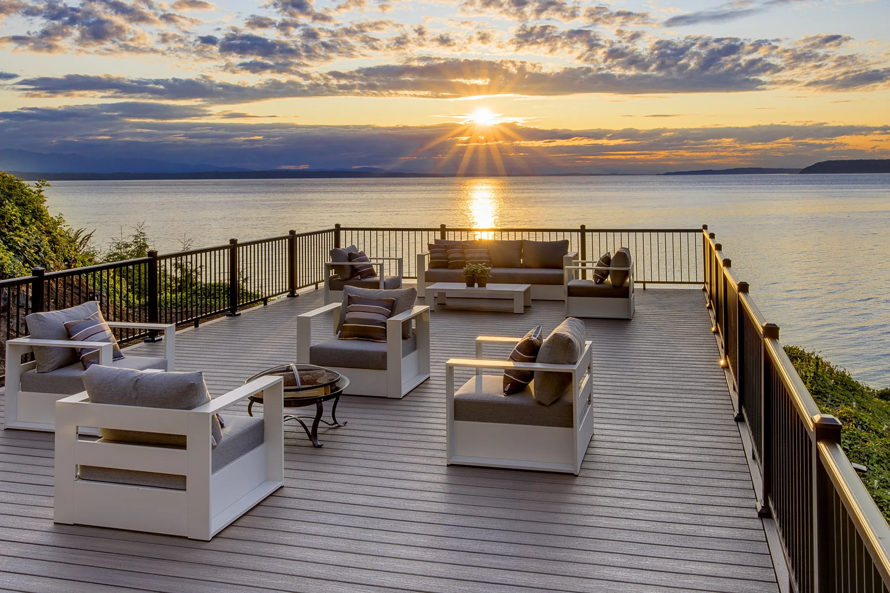 Seattle luxury home staging featuring a waterfront terrace with multiple lounge groupings as the sun sets over Puget Sound