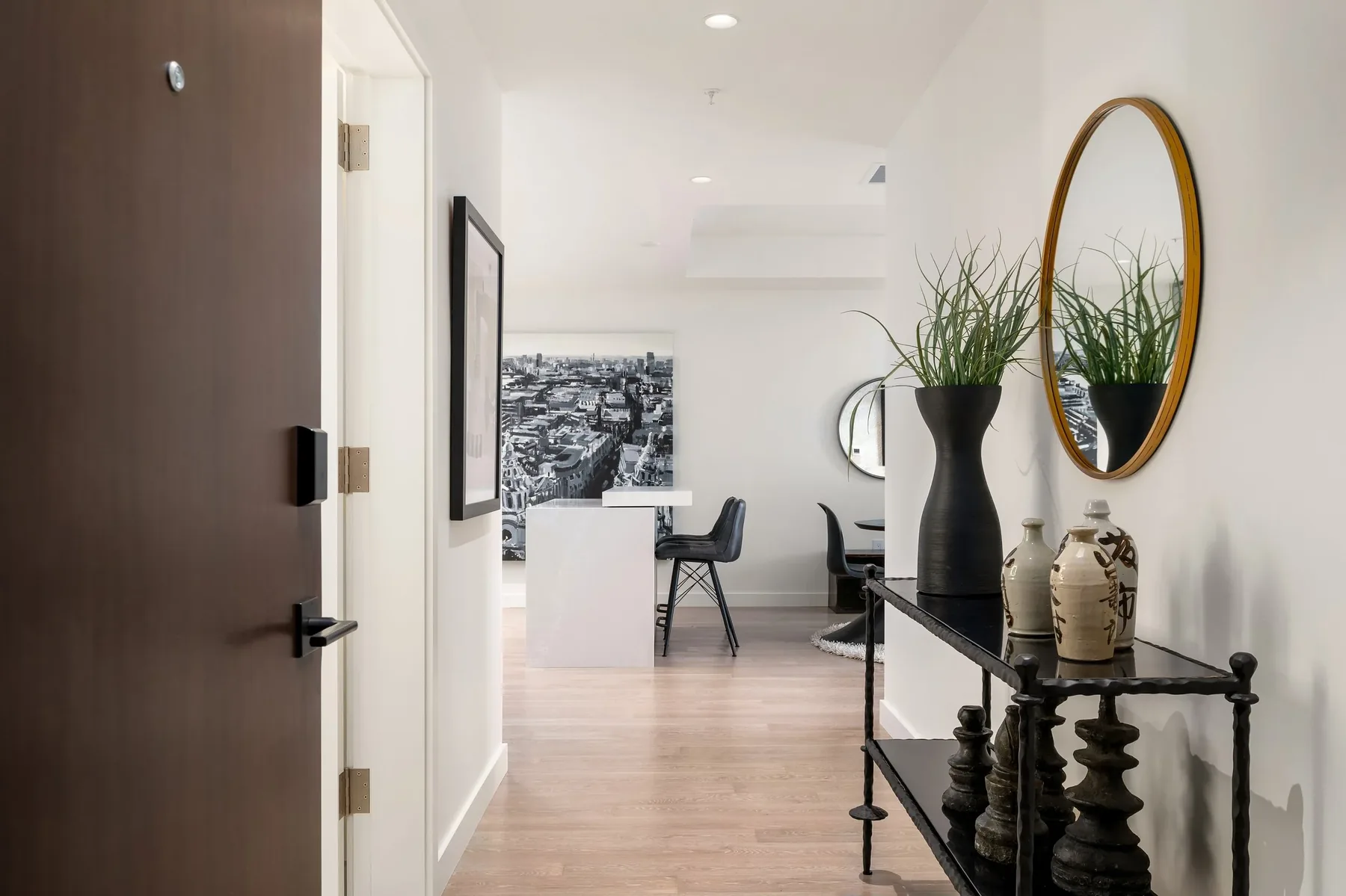 Modern condo entry staged by RD Interiors with a round mirror, console table, and a sightline through to the kitchen