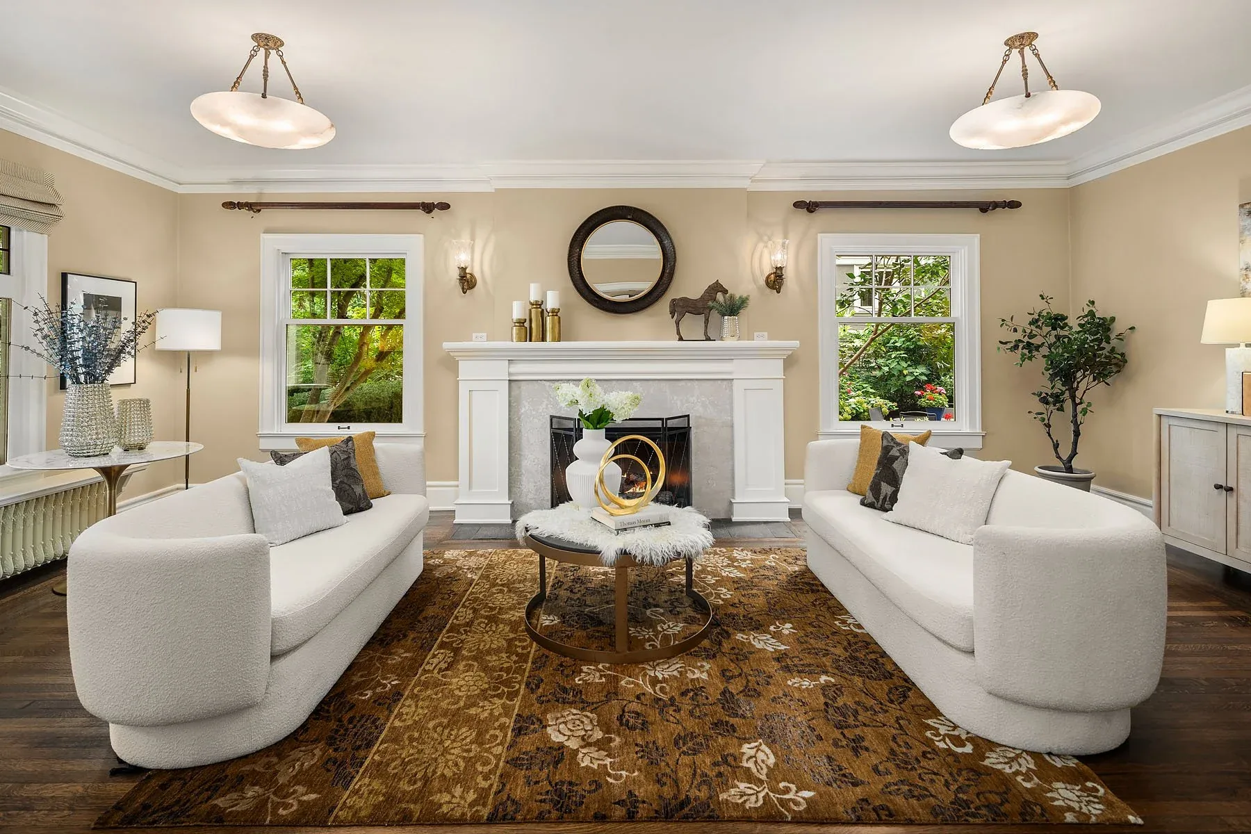 Capitol Hill home staging by RD Interiors with twin curved sofas, a marble fireplace, and a round mirror in a sunlit living room