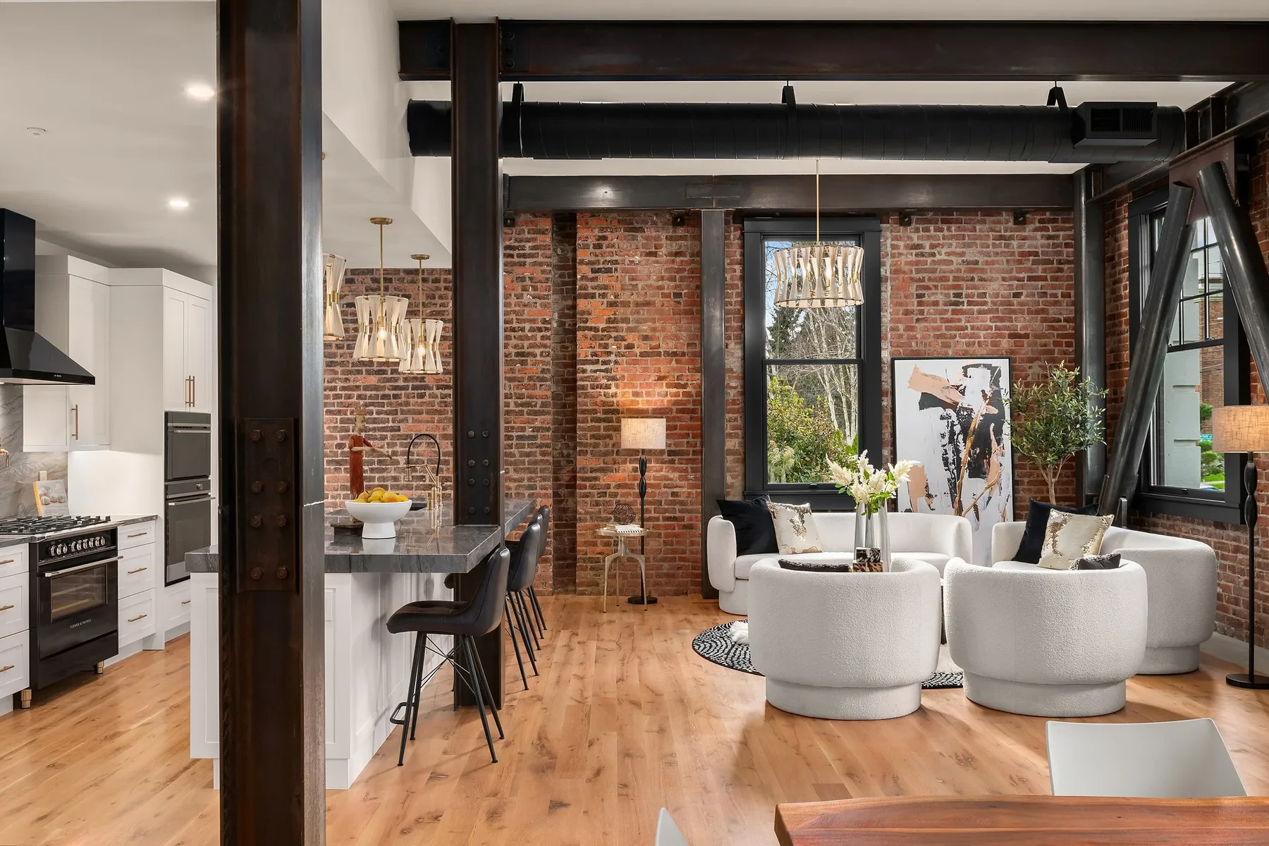 Living room staged with curved bouclé swivel chairs, exposed brick, and diagonal steel structural bracing