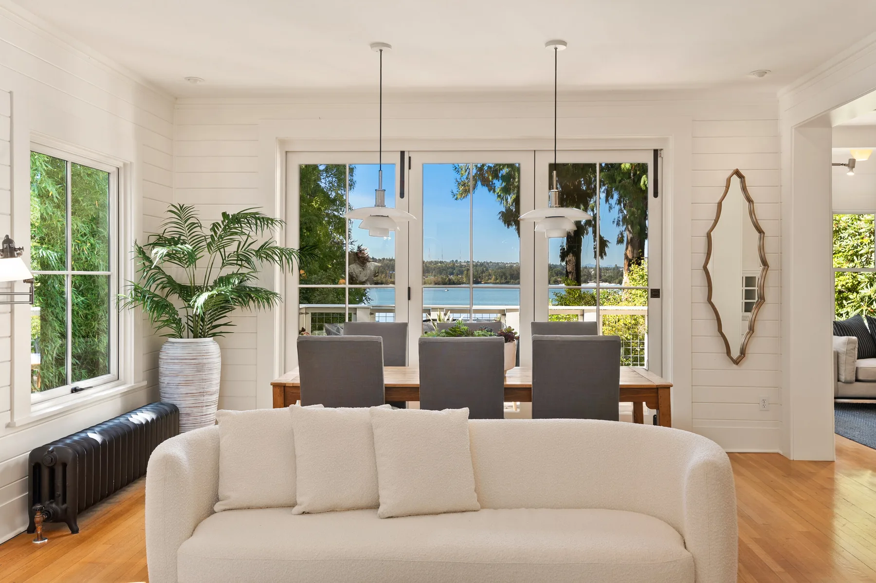 Seattle luxury home staging featuring a shiplap living and dining room with a curved sofa, antique radiator, and sliding doors framing the lake